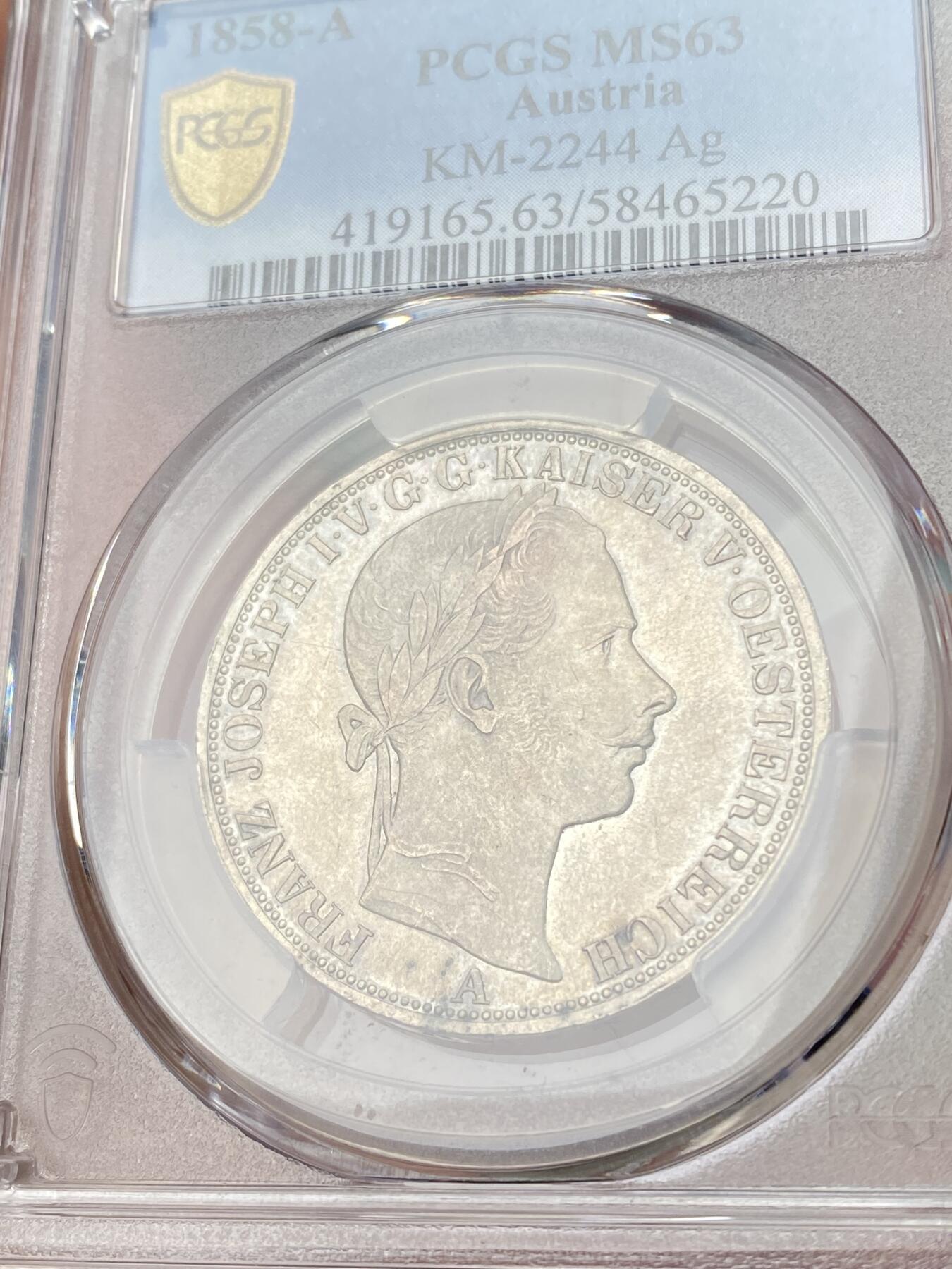 万国钱币拍卖第064期 PCGS MS63 1858年奥地利弗朗茨一世双头鹰流通1泰勒 维也纳货币协议的产物 与德国联合泰勒形制相同 车轮转光欧陆原味淡彩环绕极美收藏品质