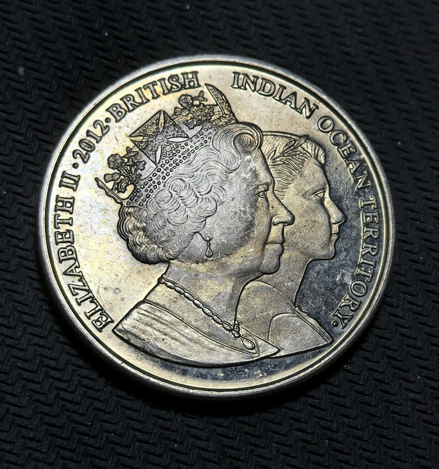 外国优质银币克朗币纪念章，每周六晚九点倒数截拍，满百包邮可寄存，持续收拍 英属印度洋领地2012年2镑纪念币，为纪念伊丽莎白二世登基钻禧发行，正面是女王不同时期双肖像，背面定格其幼年骑马场景，致敬女王一生与君主生涯。