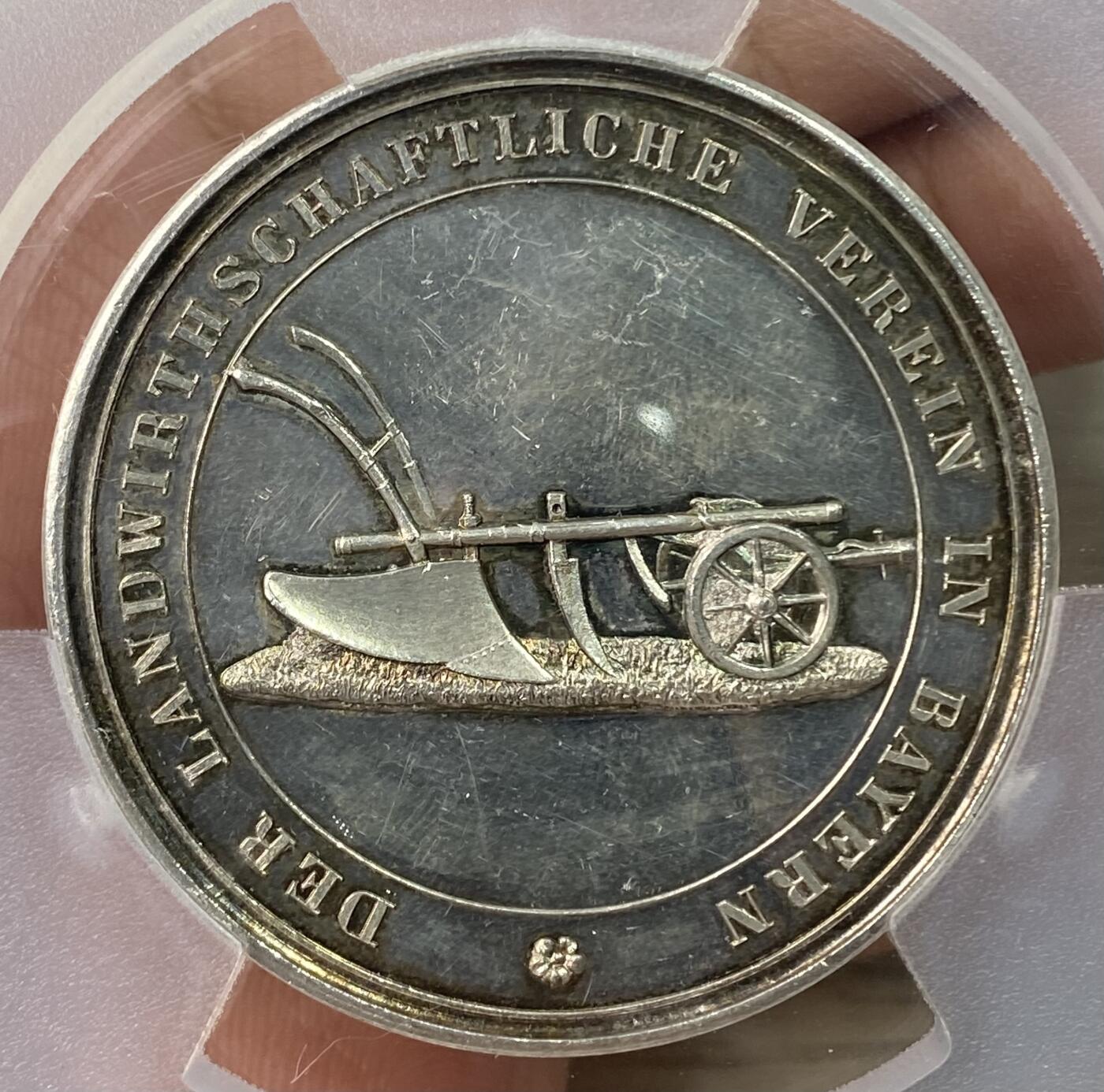 万国钱币拍卖第064期 PCGS SP63 1864-86年间德国巴伐利亚路德维希二世时期农业奖励大银章 小型易得 大规格首见 极美全镜面精铸七彩色调环绕 背面寓意丰收的高浮雕植物藤蔓精致美丽