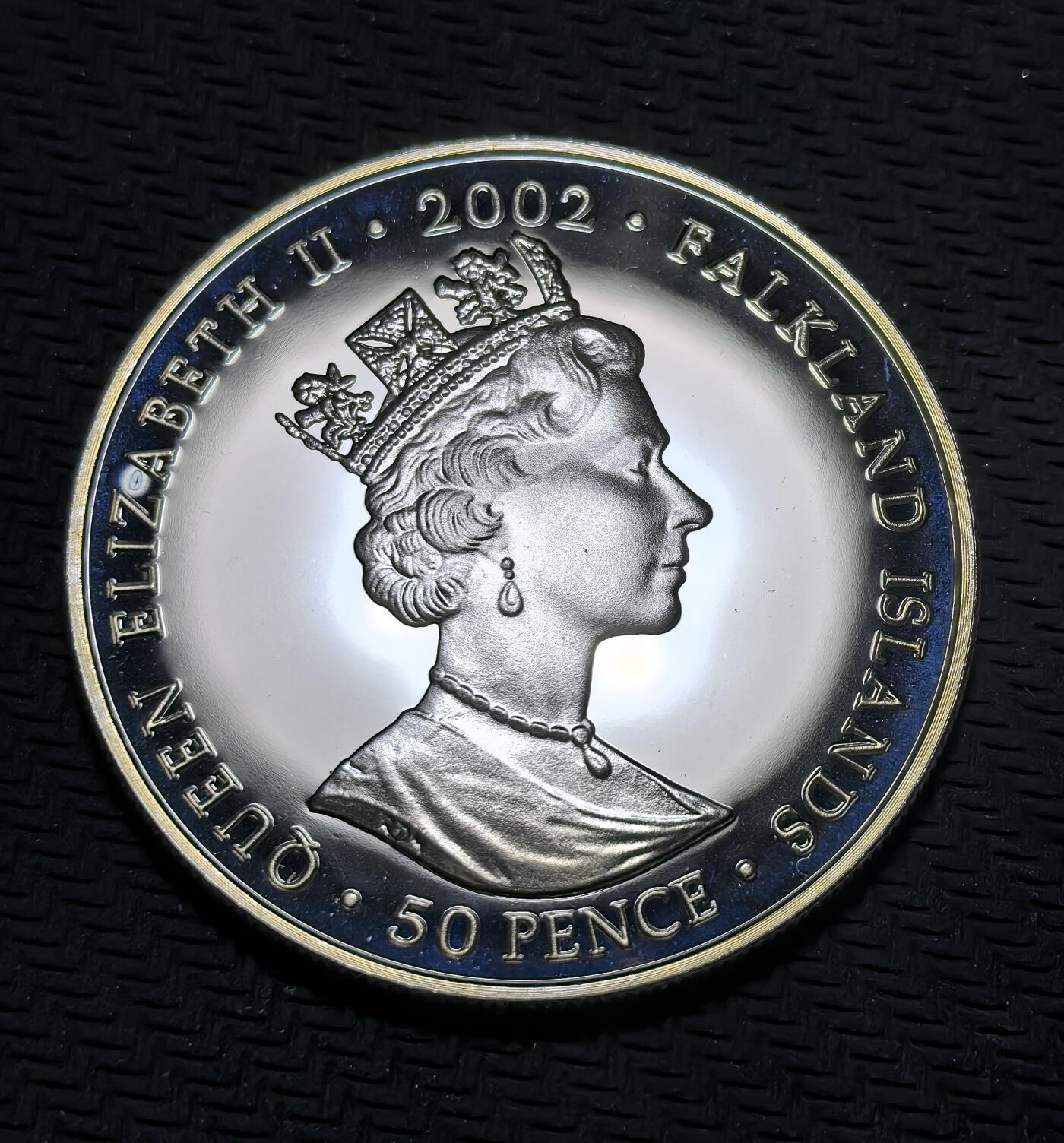 外国优质银币克朗币纪念章，每周六晚九点倒数截拍，满百包邮可寄存，持续收拍 福克兰群岛2002年50 便士纪念币，为纪念伊丽莎白二世登基金禧（1952-2002，即位 50 周年）发行，正面是女王标准肖像，背面以加冕马车配彩旗，致敬女王半世纪君主生涯。
