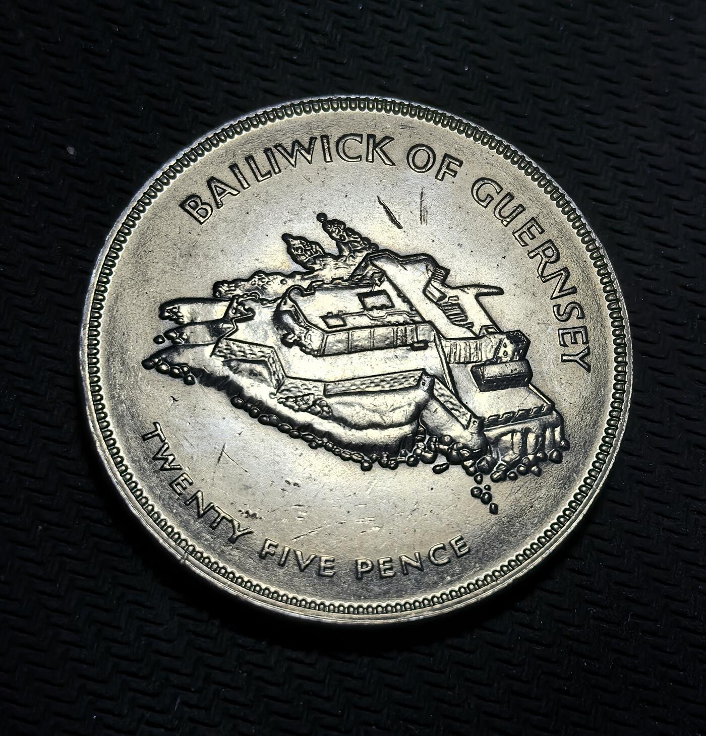 外国优质银币克朗币纪念章，每周六晚九点倒数截拍，满百包邮可寄存，持续收拍 根西岛1977年伊丽莎白二世登基银禧 25 便士纪念币，正面是女王肖像，背面为根西岛城堡地标，见证英王室与海峡群岛的联结。