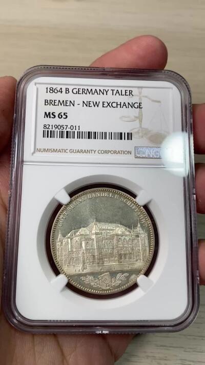 万国钱币拍卖第064期 NGC MS65 1864年不来梅证券交易所泰勒 名誉品种，来自汉诺威厂的顶级工艺，双面香槟金彩裹身霜感极强高点堪称完美，仅单年发行5000枚，BU品质极其罕见。不来梅自由市为纪念该新交易所于1864年11月5日开业而发行，正面为交易所景观，下方为饰以橡树枝叶的不来梅市徽，上方刊德文“上帝保佑贸易与航运”这座美丽的新哥特风格建筑在1943年毁于战火，庆幸的是还能在此币上欣赏她的美丽。