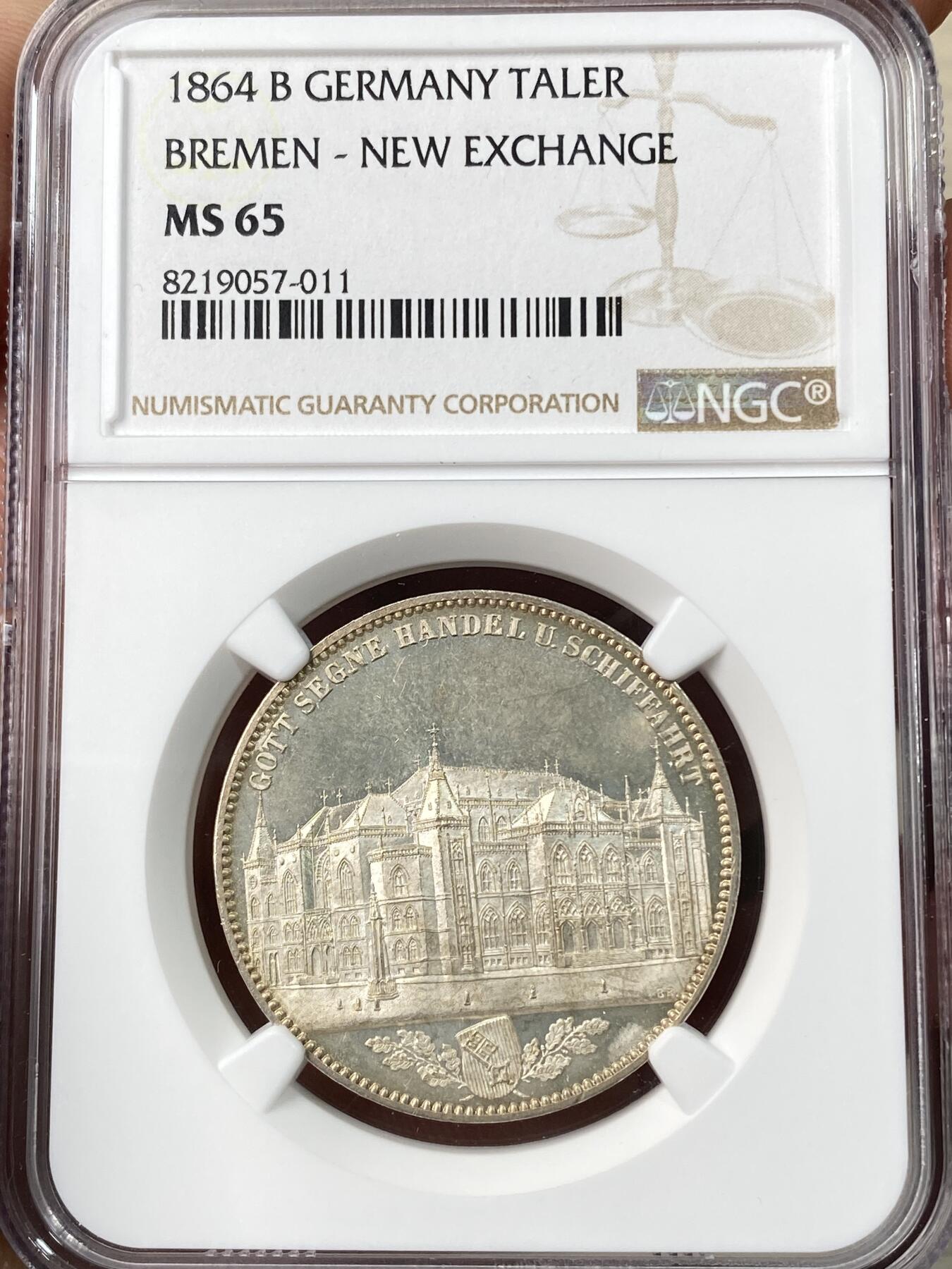 万国钱币拍卖第064期 NGC MS65 1864年不来梅证券交易所泰勒 名誉品种，来自汉诺威厂的顶级工艺，双面香槟金彩裹身霜感极强高点堪称完美，仅单年发行5000枚，BU品质极其罕见。不来梅自由市为纪念该新交易所于1864年11月5日开业而发行，正面为交易所景观，下方为饰以橡树枝叶的不来梅市徽，上方刊德文“上帝保佑贸易与航运”这座美丽的新哥特风格建筑在1943年毁于战火，庆幸的是还能在此币上欣赏她的美丽。