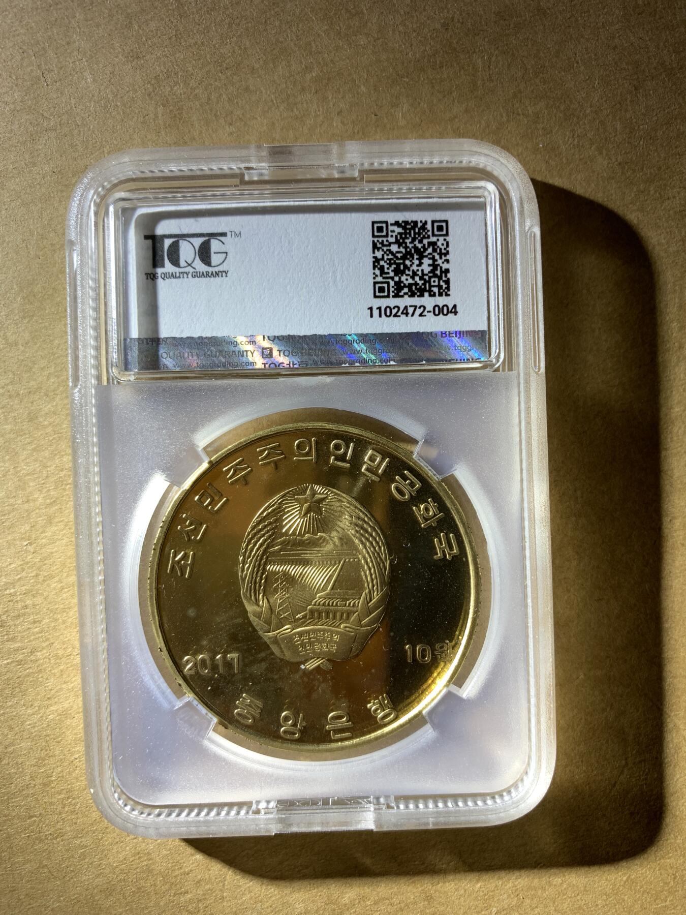 【礼羽收藏】🌏世界钱币拍卖第132期 朝鲜2017年发行的10元纪念币，纪念最高人民会议成立100周年，评级PF 67 UC（精制币，镜面深打67分）。材质是铜镍合金，金黄色调，正面有“志远”和松树图案。