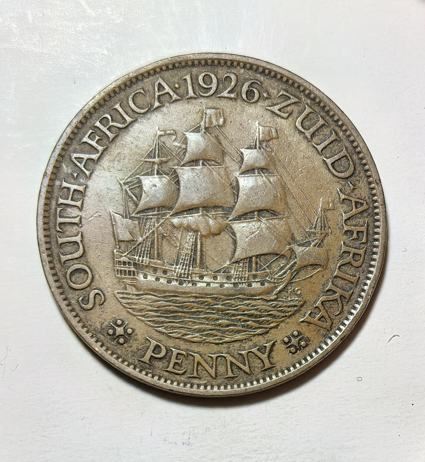 外国优质银币克朗币纪念章，每周六晚九点倒数截拍，满百包邮可寄存，持续收拍 南非联邦1926年1 便士铜币，正面为乔治五世国王像，背面是荷兰东印度公司帆船，是英联邦自治领南非的双语（英 / 阿非利卡语）流通币，见证了南非殖民史与本土认同。