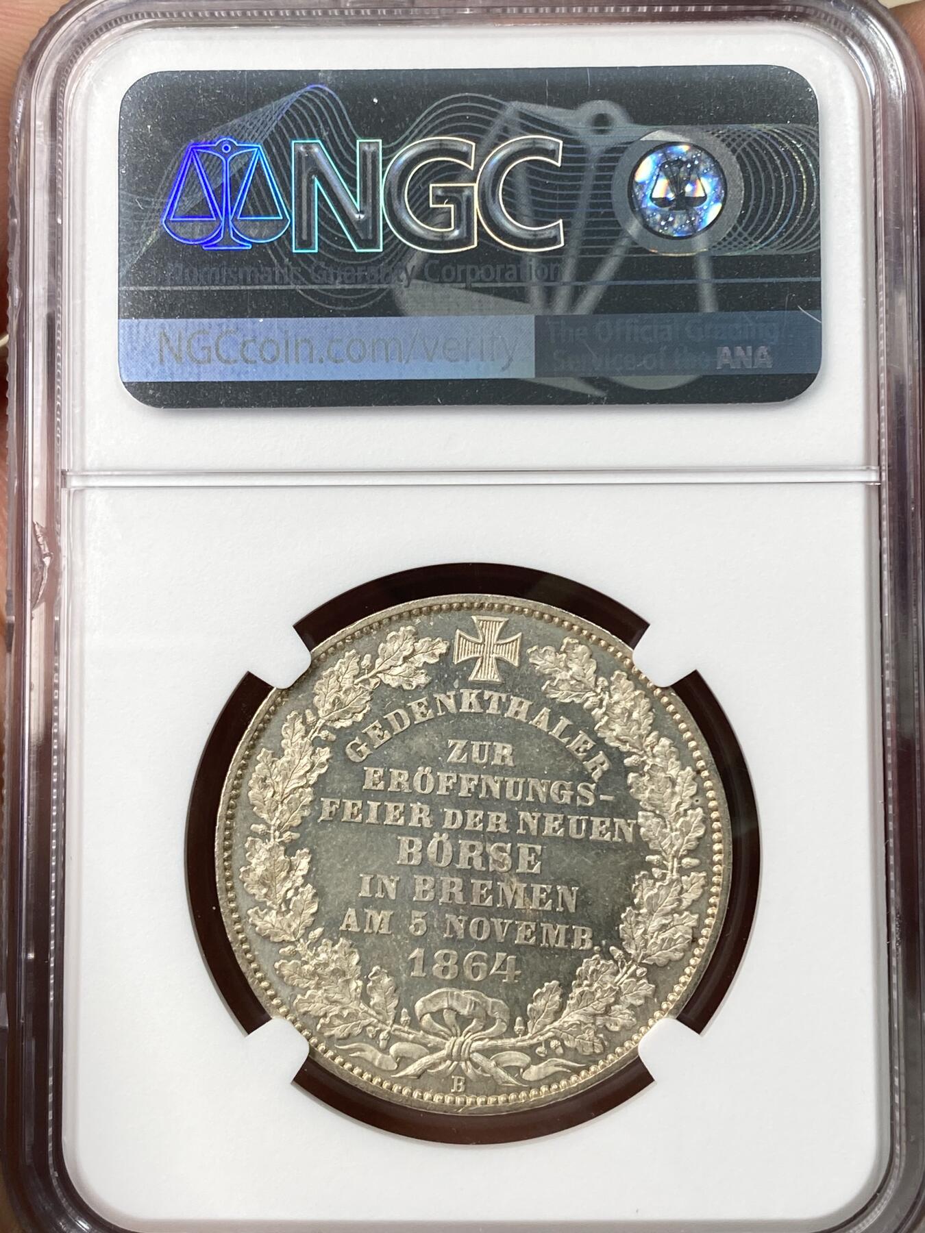 万国钱币拍卖第064期 NGC MS65 1864年不来梅证券交易所泰勒 名誉品种，来自汉诺威厂的顶级工艺，双面香槟金彩裹身霜感极强高点堪称完美，仅单年发行5000枚，BU品质极其罕见。不来梅自由市为纪念该新交易所于1864年11月5日开业而发行，正面为交易所景观，下方为饰以橡树枝叶的不来梅市徽，上方刊德文“上帝保佑贸易与航运”这座美丽的新哥特风格建筑在1943年毁于战火，庆幸的是还能在此币上欣赏她的美丽。