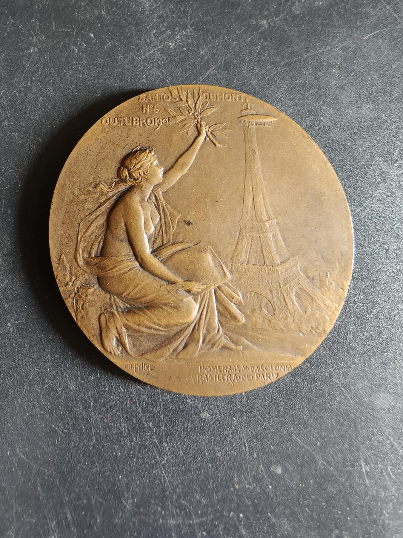 老王徽章第191期 法国驻巴黎巴西侨民直径阿尔贝托·桑托斯-杜蒙大铜章     原盒      新艺术风格航空女神形象    阿尔贝托·桑托斯·杜蒙为巴西传奇航空先驱、人类航空史的奠基人之一，被巴西尊为“航空之父”，发明了飞艇并成功于1906年驾驶6号飞艇完成环绕埃菲尔铁塔飞行一圈并返航         大师皮列作品       直径50mm    重量56g 