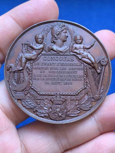 《竞宝斋》第477场 周日，周一 2场连拍 （全场包邮）欢迎送拍 - 1849年布鲁塞尔官方合唱比赛纪念铜章，该章使用双面高浮雕，是比利时音乐与王室题材的经典纪念章藏品，正面为利奥波德一世国王，背面主体刻有比赛相关法语铭文，牌匾周围环绕月桂枝和花环，底部刻有皇室皇冠纹饰，体现官方赞助，牌匾上方有古典风格人物侧面像，与小天使、乐器元素呼应，典雅的艺术庆典氛围。少见品种，品相佳，值得收藏。直径50mm，重49.4g。