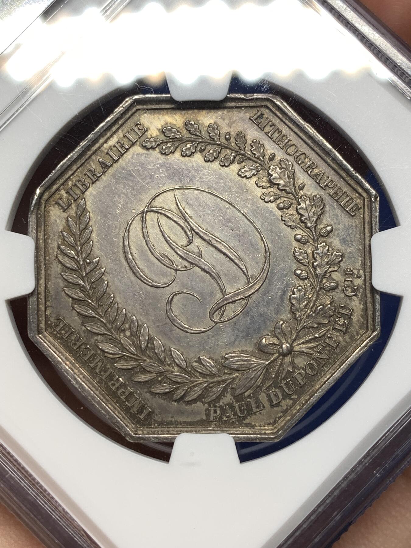 《竞宝斋》第477场 周日，周一 2场连拍 （全场包邮）欢迎送拍 NGC MS62 法国1836年巴黎印刷商发行的古腾堡与塞纳菲尔德纪念八角银质代币，19世纪欧洲印刷术题材稀缺藏品，巴黎印刷博物馆、法国国家图书馆有同款银质馆藏藏品。历史艺术价值高，极具收藏价值。早期蜜蜂边铭难得。直径：35.5mm，重：19.07g，加厚盒。