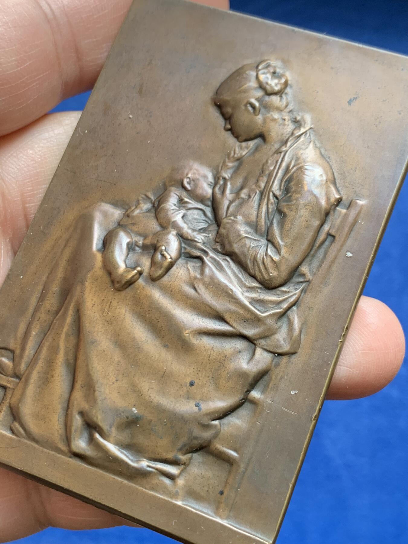 《竞宝斋》第477场 周日，周一 2场连拍 （全场包邮）欢迎送拍 SAMF《母爱》特蕾莎（THERESE 1 MAI 1899）协会作品3号 编号237 本章为法国艺术家亚历山大·沙尔庞捷（Alexandre Charpentier，1856–1909）创作之《母爱》题材铜章，属SAMF（法国艺术家奖章协会）原作发行于1900年。该作品源自艺术家此前创作的“年轻母亲哺乳幼子”浮雕主题，并曾在1883年法国艺术家协会沙龙展出并获奖。143.8克，52.8*80.5