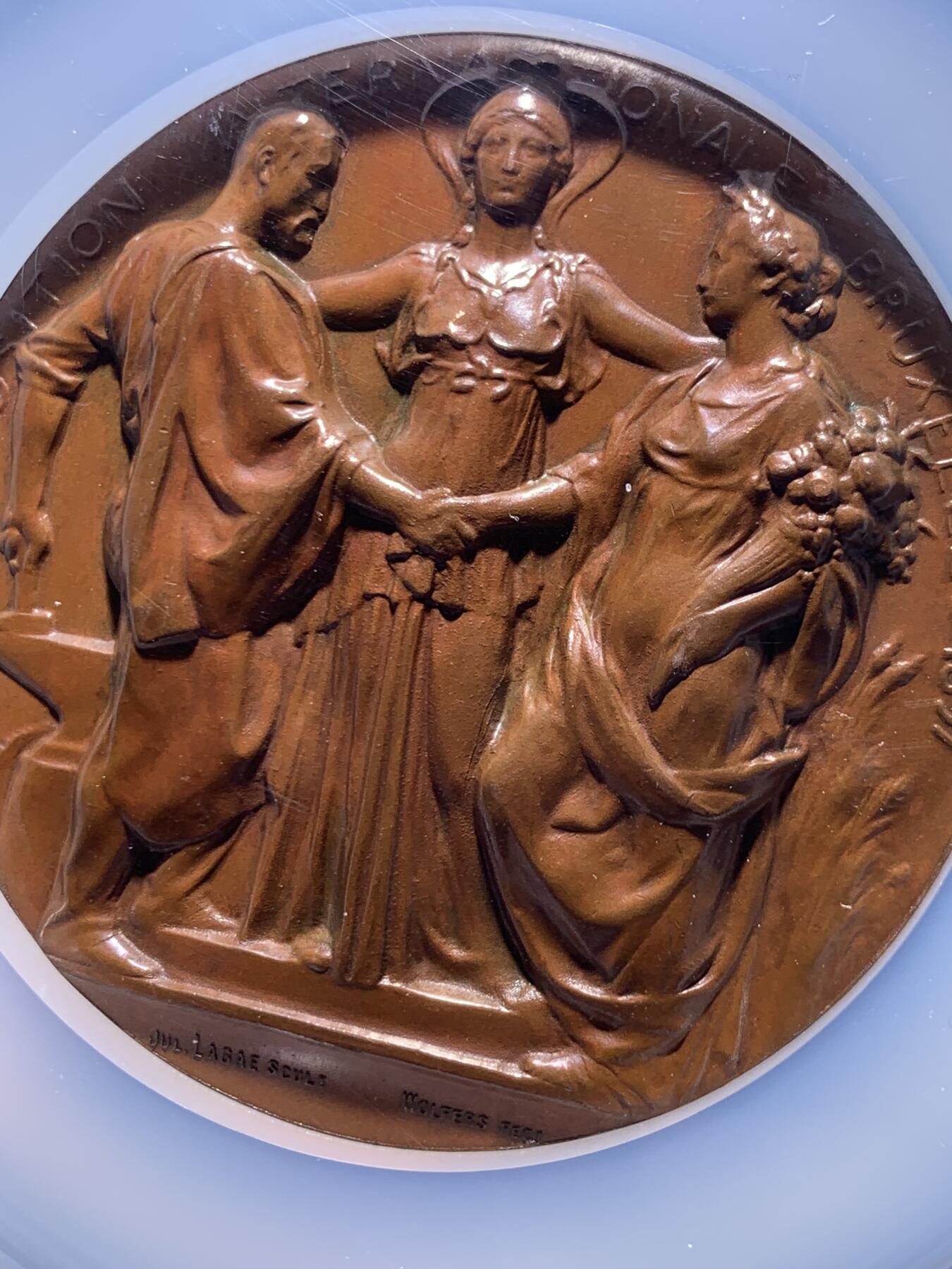 《竞宝斋》第478场 周日，周一 2场连拍 （全场包邮）欢迎送拍 NGC MS65BN 高分 1897年布鲁塞尔国际博览会纪念大铜章，加大加厚盒。由比利时著名雕刻师Julius Lagae设计，Wolters造币厂铸造，是19世纪万国博览会题材章牌的经典藏品，正面中心图案为布鲁塞尔女性形象，左右分别代表工业、农业，三人握手寓意产业与城市的融合，背面图案为王室纹章，两侧为狮子护佑纹章，下边铭文译为”团结就是力量“国家箴言。