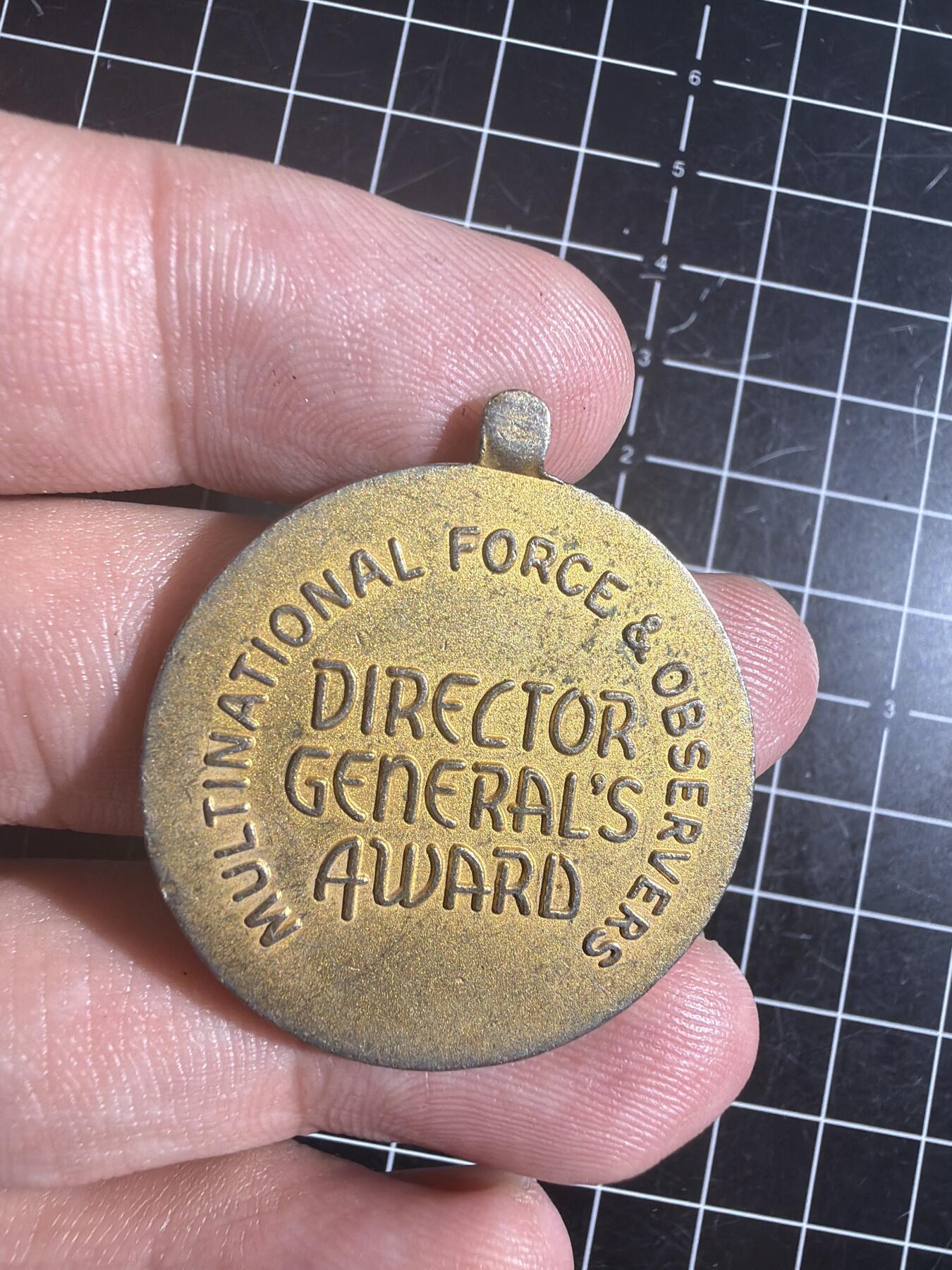 古冰库章牌勋赏收藏0起拍卖 联合国多国部队纪念章，铜质徽章挂件，直径约3.5cm，厚实有分量。正面刻“UNITED IN SERVICE FOR PEACE”，背面“MULTINATIONAL FORCE & OBSERVERS DIRECTOR GENERAL'S AWARD