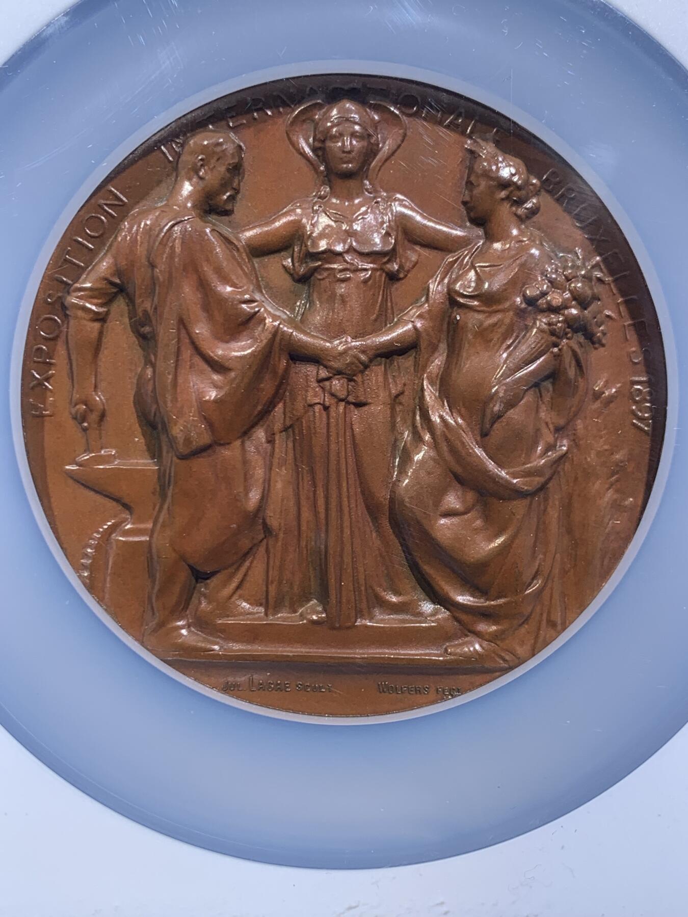 《竞宝斋》第478场 周日，周一 2场连拍 （全场包邮）欢迎送拍 NGC MS65BN 高分 1897年布鲁塞尔国际博览会纪念大铜章，加大加厚盒。由比利时著名雕刻师Julius Lagae设计，Wolters造币厂铸造，是19世纪万国博览会题材章牌的经典藏品，正面中心图案为布鲁塞尔女性形象，左右分别代表工业、农业，三人握手寓意产业与城市的融合，背面图案为王室纹章，两侧为狮子护佑纹章，下边铭文译为”团结就是力量“国家箴言。