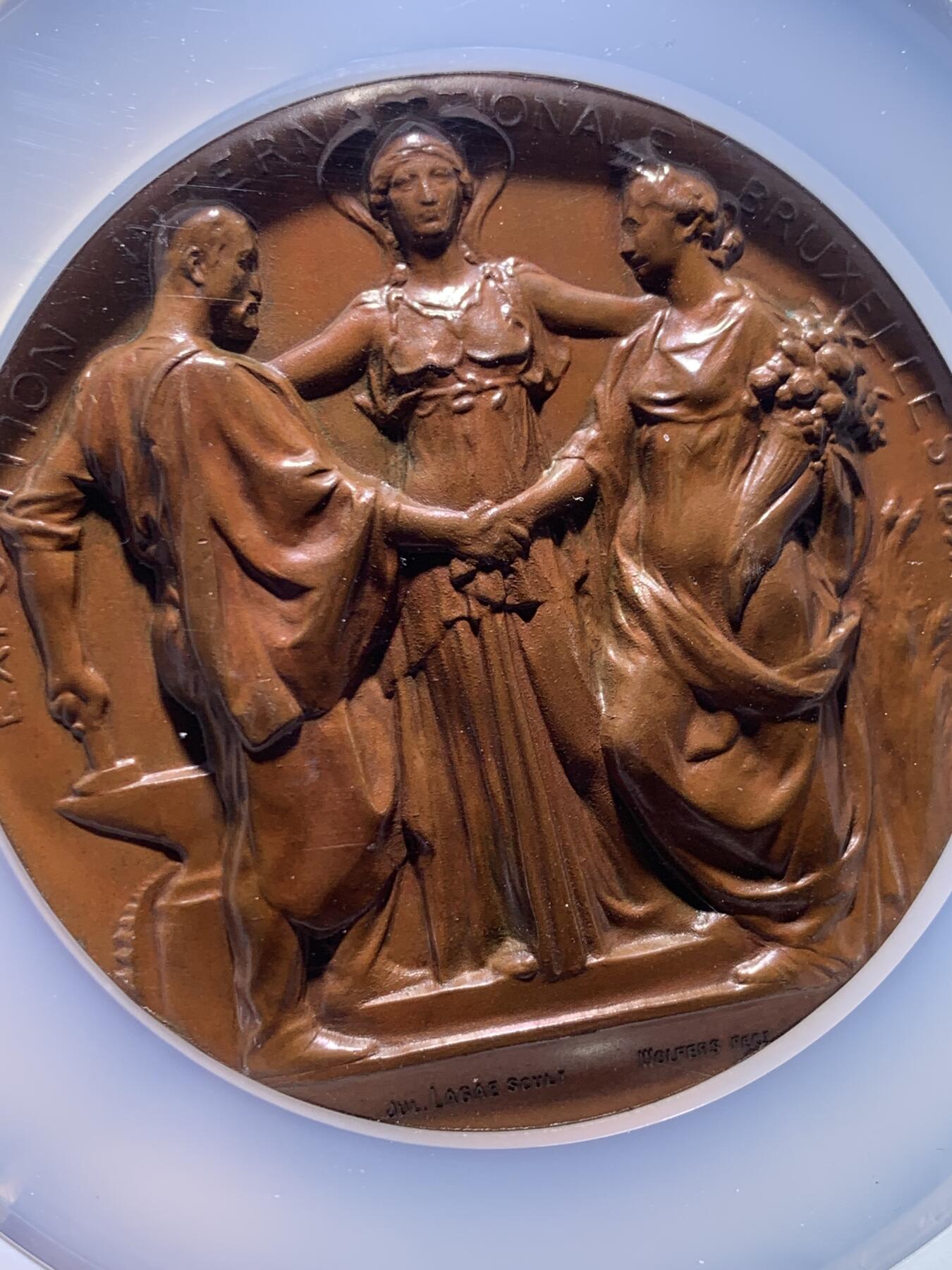 《竞宝斋》第478场 周日，周一 2场连拍 （全场包邮）欢迎送拍 NGC MS65BN 高分 1897年布鲁塞尔国际博览会纪念大铜章，加大加厚盒。由比利时著名雕刻师Julius Lagae设计，Wolters造币厂铸造，是19世纪万国博览会题材章牌的经典藏品，正面中心图案为布鲁塞尔女性形象，左右分别代表工业、农业，三人握手寓意产业与城市的融合，背面图案为王室纹章，两侧为狮子护佑纹章，下边铭文译为”团结就是力量“国家箴言。