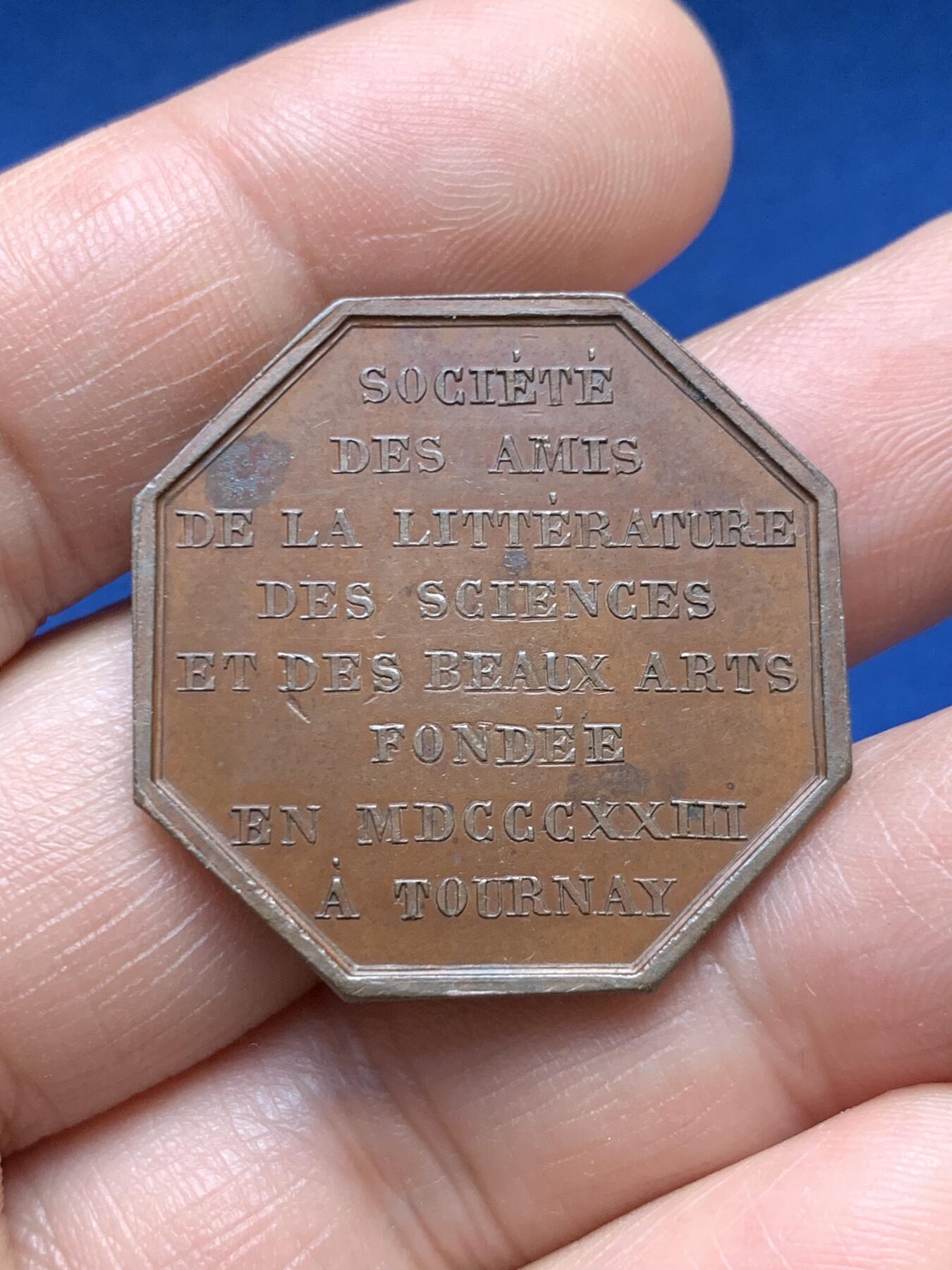 《竞宝斋》第478场 周日，周一 2场连拍 （全场包邮）欢迎送拍 1823年比利时图尔奈文学、科学与美术之友协会八角形纪念章，存世量较少，正面刻有里拉琴（代表文学艺术），月桂枝（象征荣誉），祭坛式纹饰搭配放射状星芒。19世纪新古典艺术主义，具有较高的收藏价值。直径：31.3mm，重：11.55g