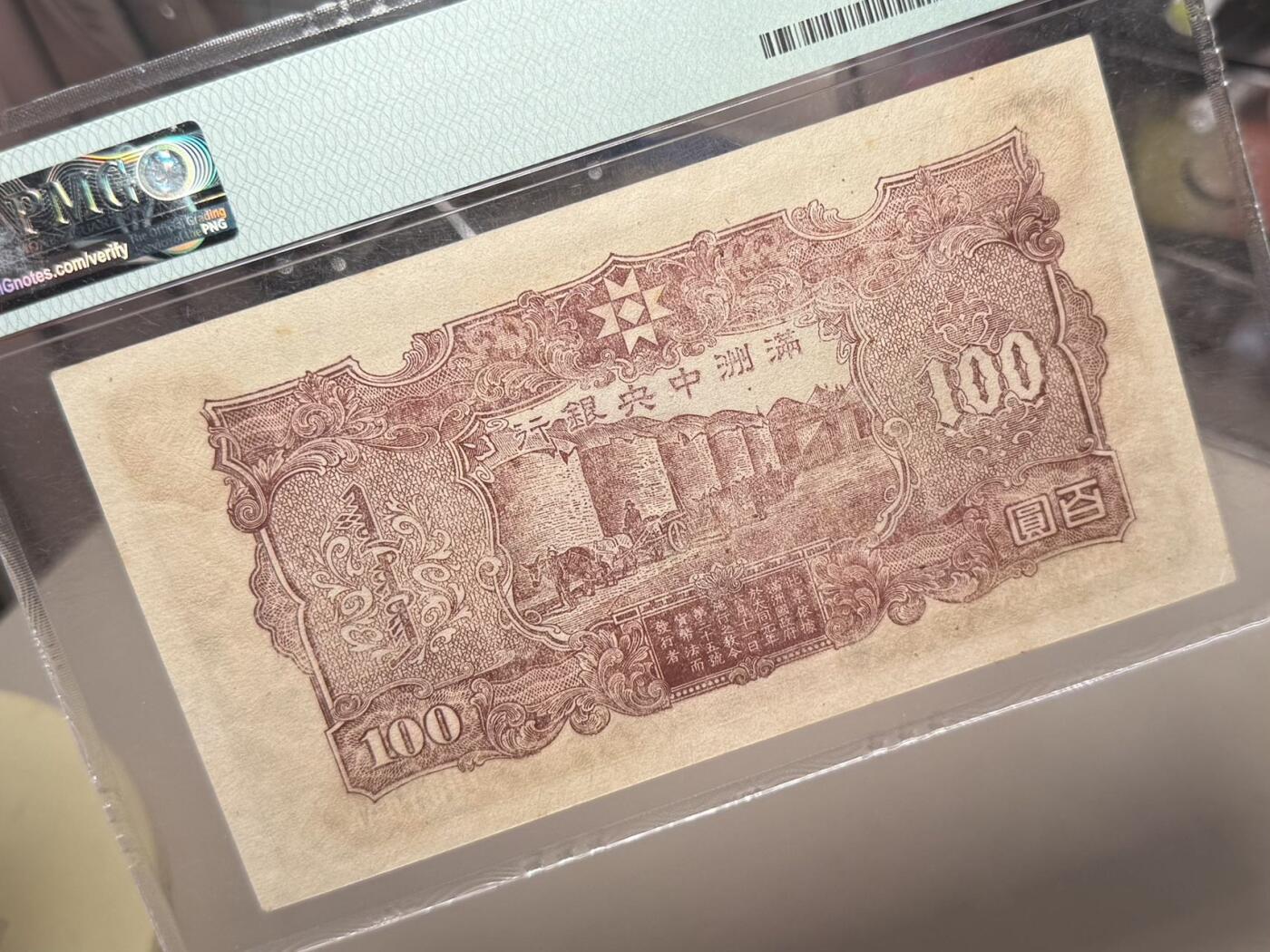 【乾奕收藏】出民国33年1944年满洲中央银行百圆，号码全程无47，正面孔子大殿，同分数里居中度较优秀的一枚，背面粮仓图案，美国PMG58分，民国纸币经过80年能保存如此品相实属难得，喜欢的老板不要错过，评级币一切以分数为准，售出非假不退
