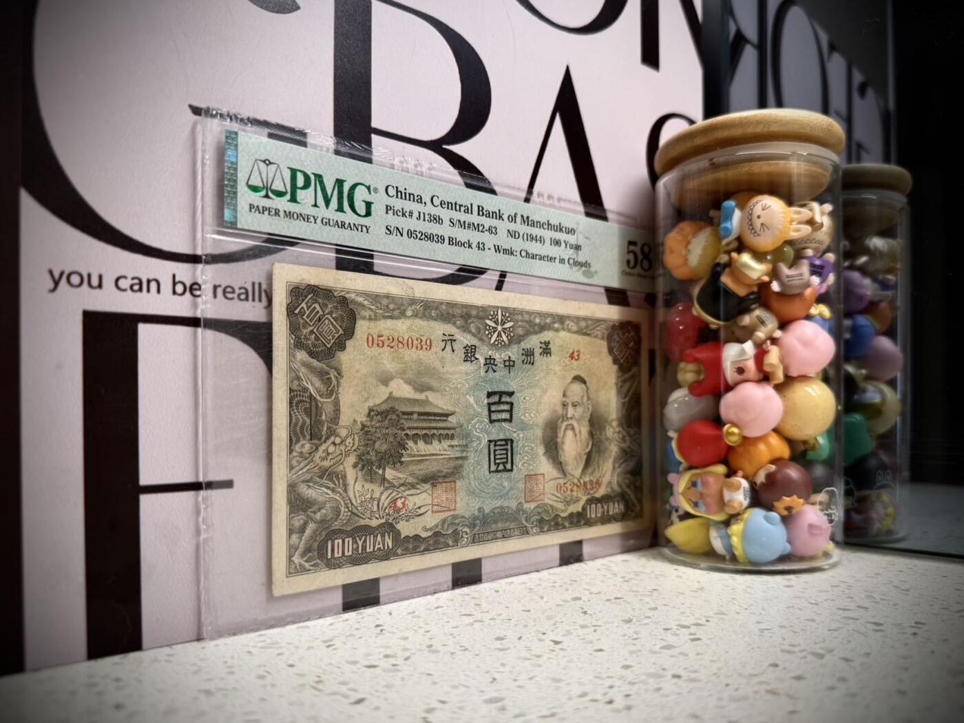 （自动截拍）PMG评级民国纸币专拍第20260407期，全场包邮 【乾奕收藏】出民国33年1944年满洲中央银行百圆，号码全程无47，正面孔子大殿，同分数里居中度较优秀的一枚，背面粮仓图案，美国PMG58分