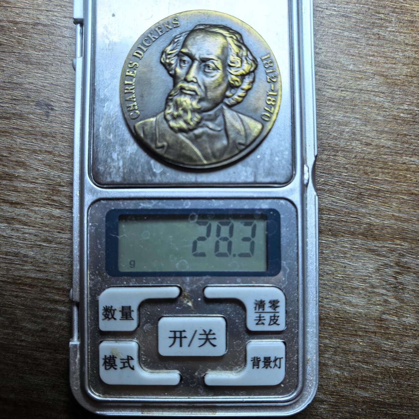  这是一枚纪念英国文豪查尔斯·狄更斯（Charles Dickens）的铜质纪念章，属于文学主题收藏品类