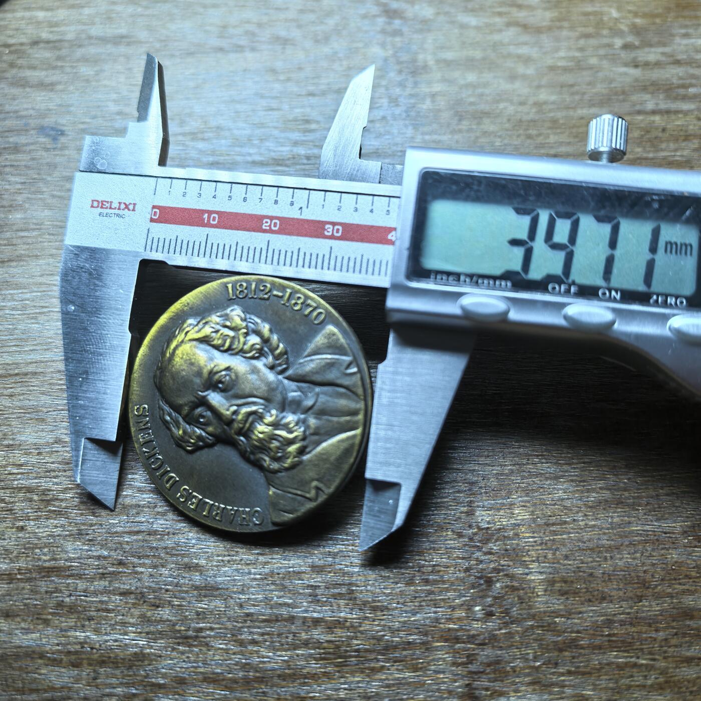  这是一枚纪念英国文豪查尔斯·狄更斯（Charles Dickens）的铜质纪念章，属于文学主题收藏品类