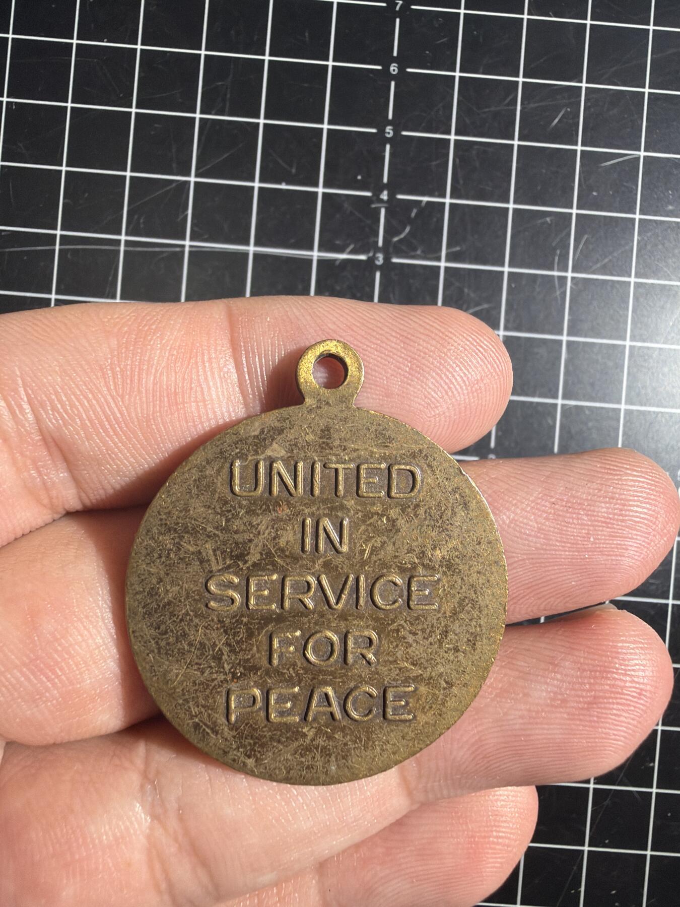 古冰库章牌勋赏收藏0起拍卖 联合国多国部队纪念章，铜质徽章挂件，直径约3.5cm，厚实有分量。正面刻“UNITED IN SERVICE FOR PEACE”，背面“MULTINATIONAL FORCE & OBSERVERS DIRECTOR GENERAL'S AWARD