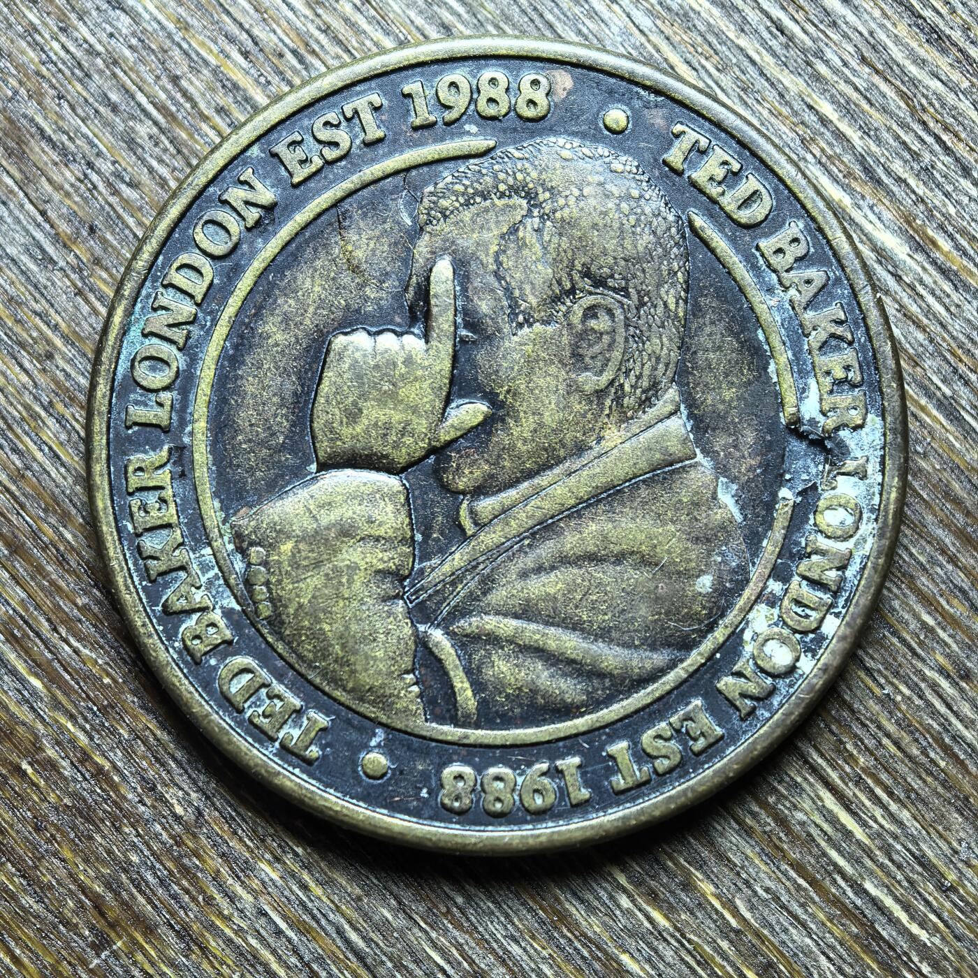 （向佐同款手势）英国时尚品牌 Ted Baker 的品牌纪念/广告代币（Token），不是法定流通货币。