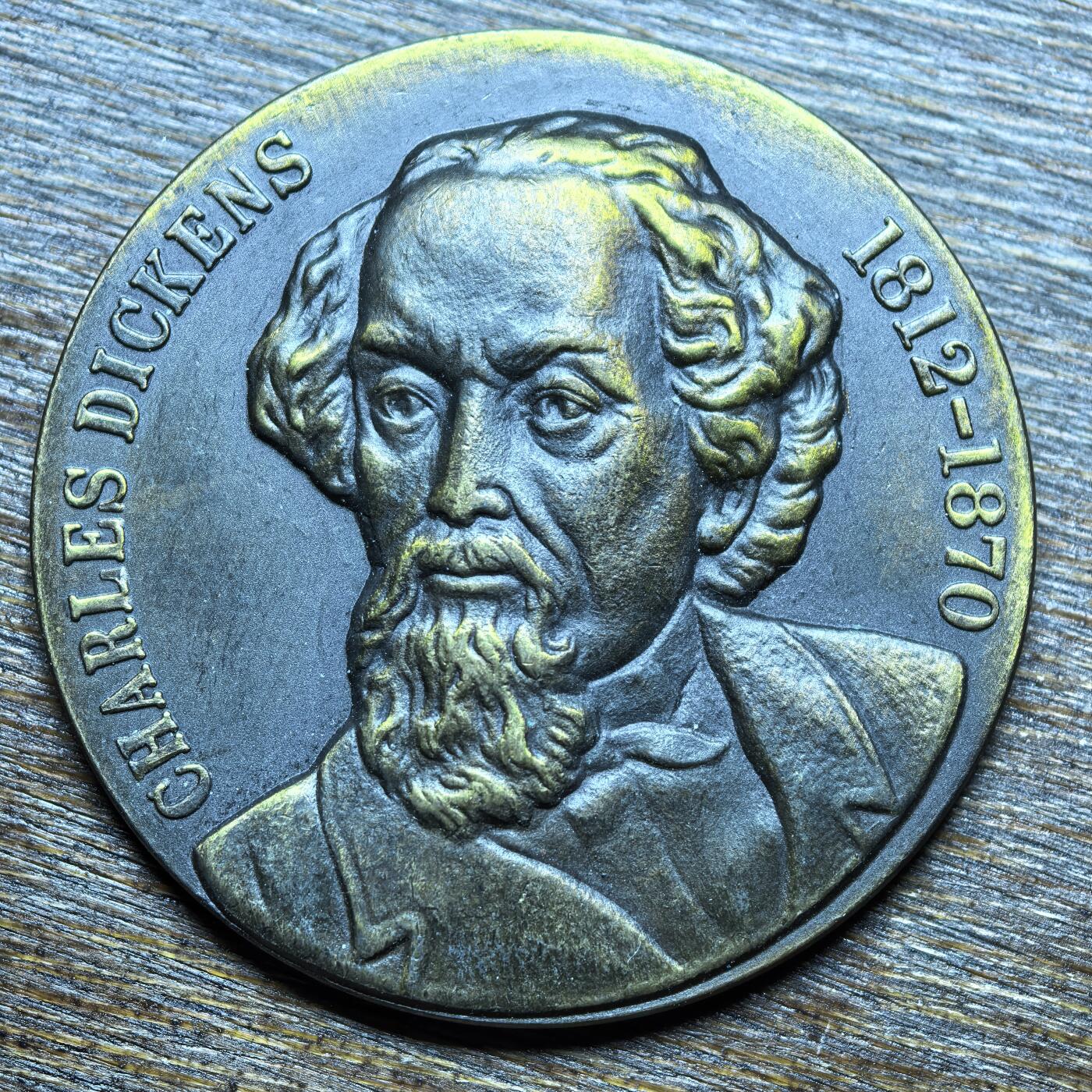  这是一枚纪念英国文豪查尔斯·狄更斯（Charles Dickens）的铜质纪念章，属于文学主题收藏品类