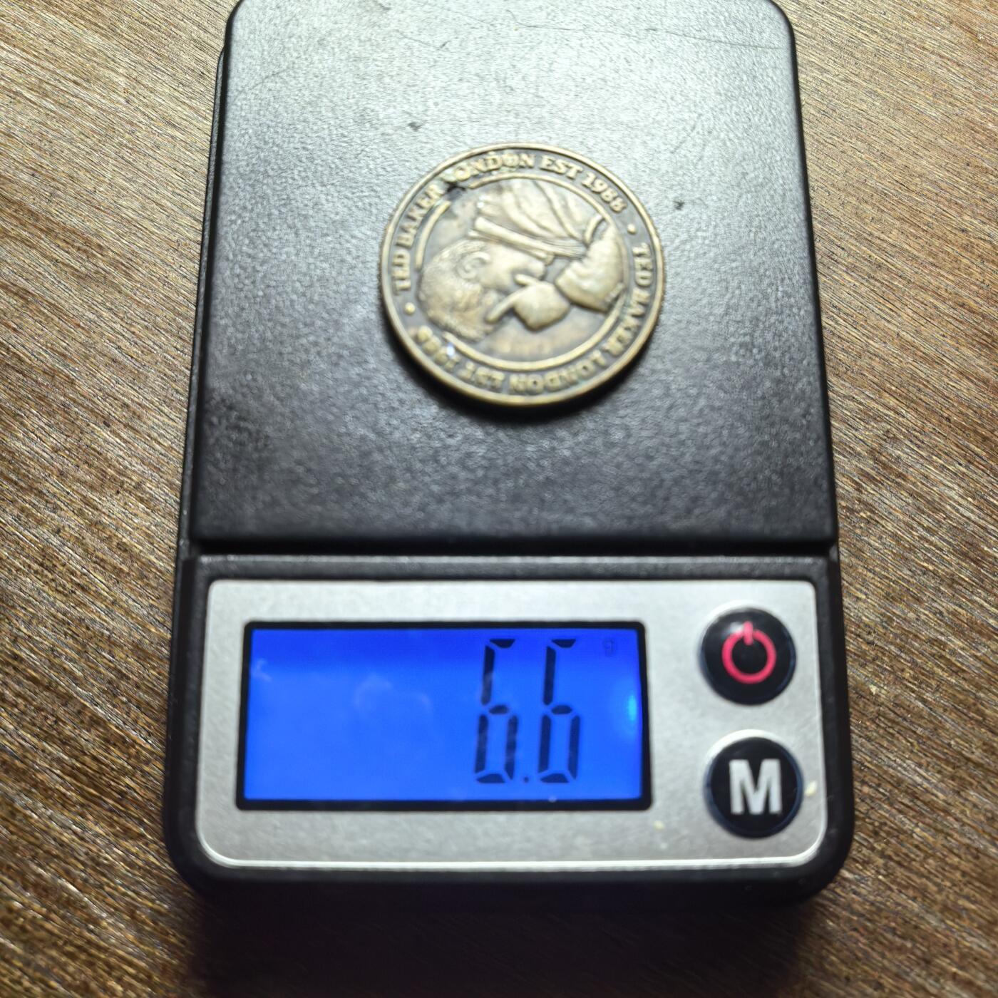 （向佐同款手势）英国时尚品牌 Ted Baker 的品牌纪念/广告代币（Token），不是法定流通货币。