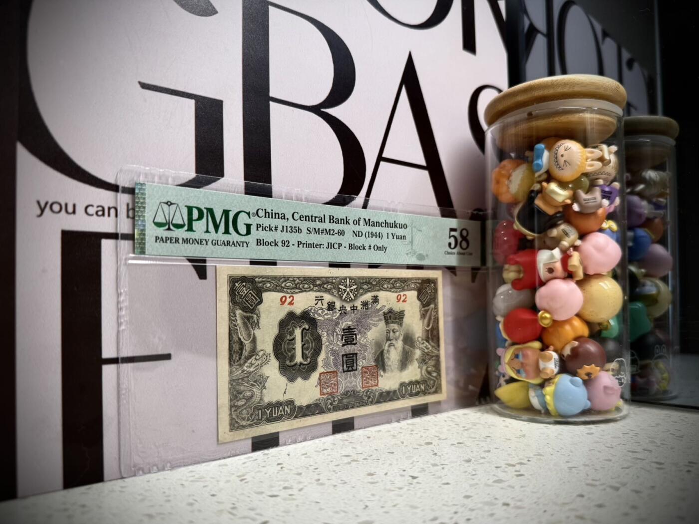 （自动截拍）PMG评级民国纸币专拍第20260411期，全场包邮 【乾奕收藏】出民国33年1944年满洲中央银行孔子像壹圆，紫凤图案，92短号，美国PMG58分