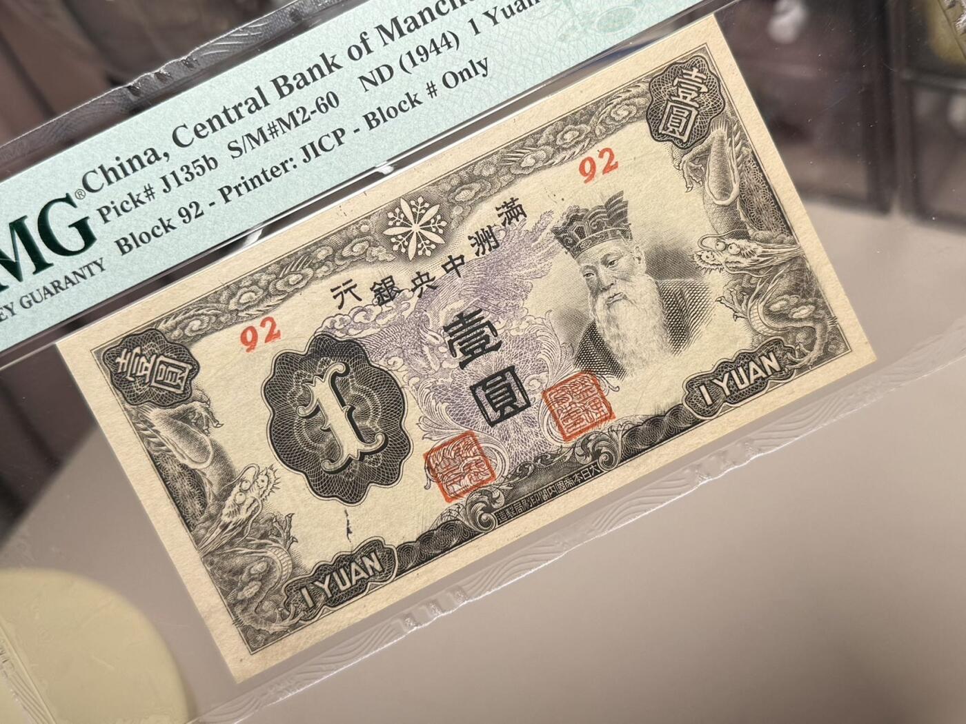 （自动截拍）PMG评级民国纸币专拍第20260411期，全场包邮 【乾奕收藏】出民国33年1944年满洲中央银行孔子像壹圆，紫凤图案，92短号，美国PMG58分