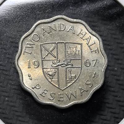 外国优质老铜币纪念币银币专场，周六晚上九点倒数截拍，满百包邮，周日发货,可寄存半年，喜欢朋友微信扫描二维码可直接参拍 - 加纳1967年可可豆2½ 比塞瓦花边形镍币。正面为加纳国徽，背面以可可豆彰显其支柱产业，铸国训 “自由与正义”，是加纳独立后流通币，见证西非国家货币自主与本土经济文化。