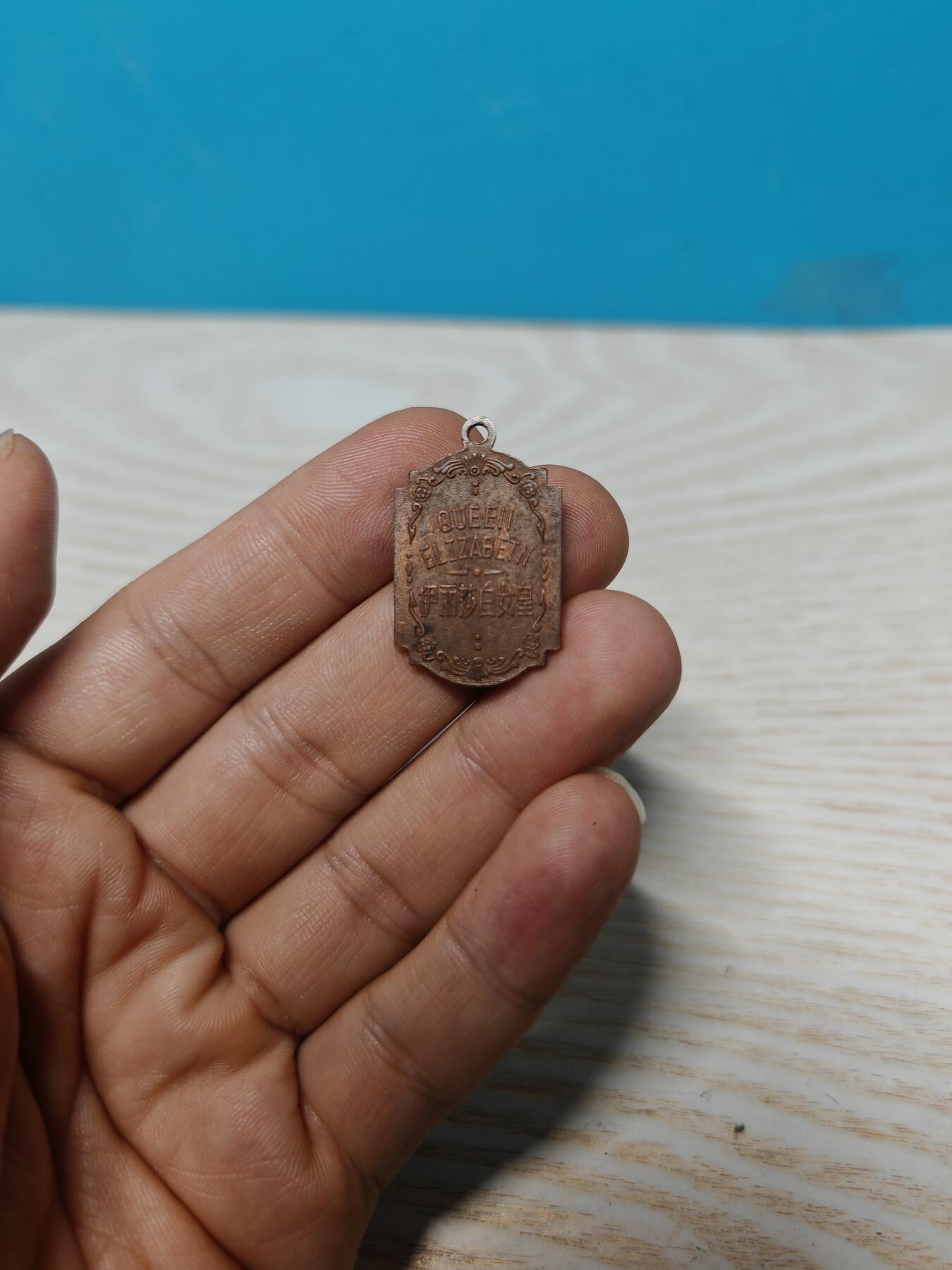 英国伊丽莎白女皇纪念章，铜质，双面浮雕，正面女王侧面像，背面QUEEN ELIZABETH及中文“伊丽莎白女皇”。尺寸约2.8cm*2cm，保存状态以图为准，有正常年代感，适合收藏