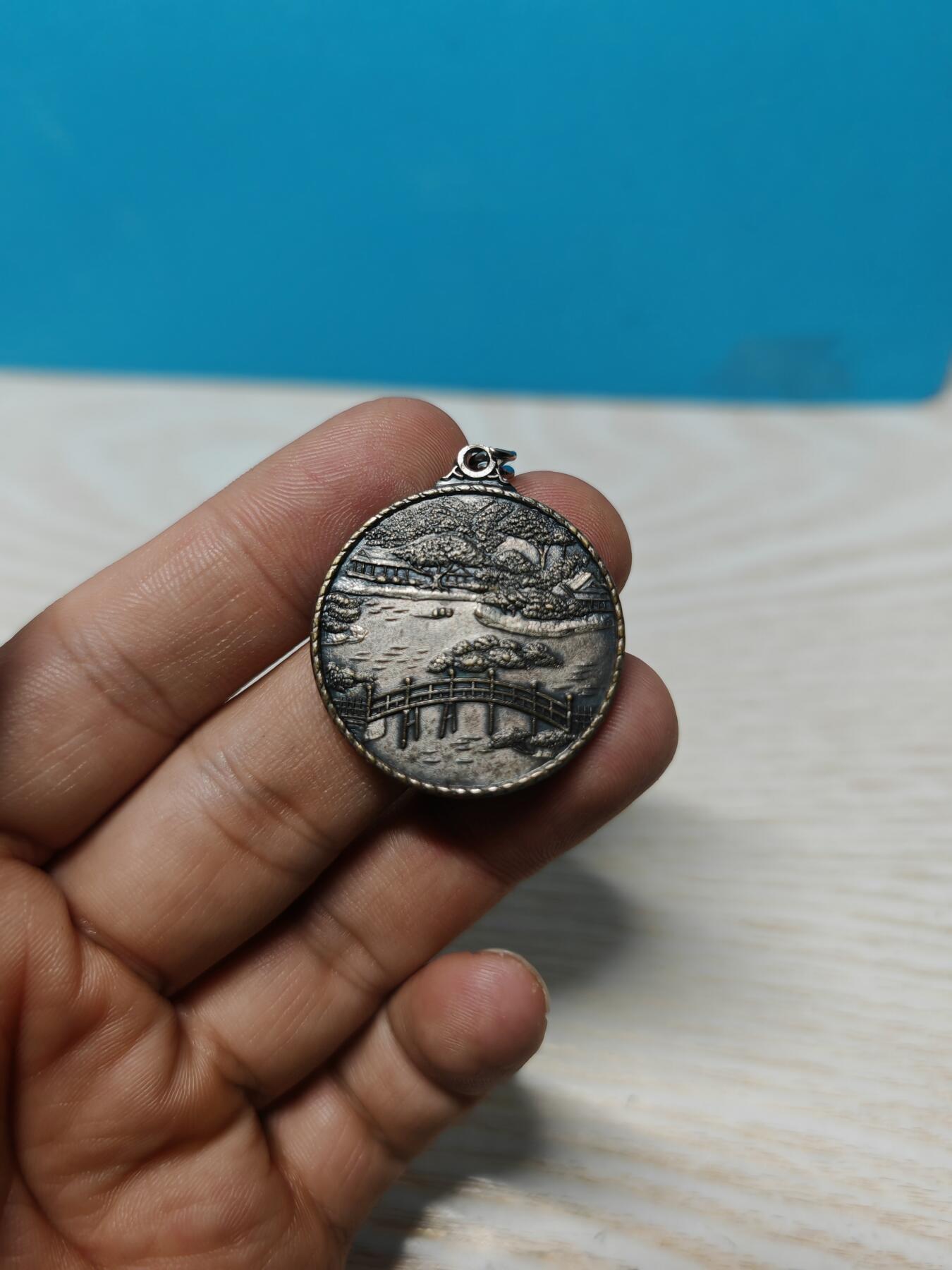 日本香川县高松市栗林公园观光纪念章，铜质，直径约32.3mm，正面“栗林公园 高松”，以及栗林公园最标志性的元素——园内有超过1400棵精心修剪的松树，背面公园风景浮雕，整体成色还可以，有正常使用痕迹，无明显磕碰。适合钱币、纪念章收藏