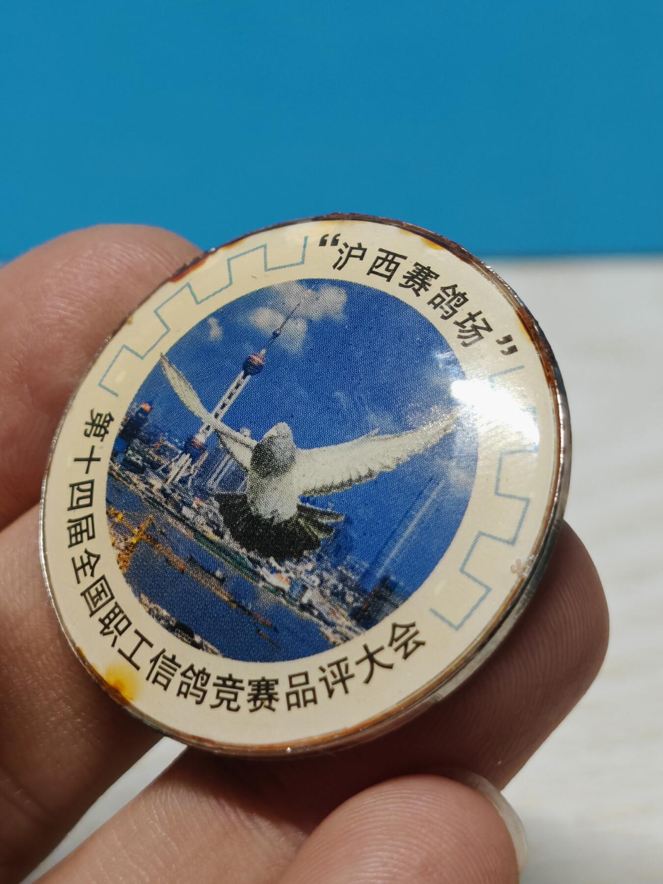 1999年第十四届全国职工信鸽竞赛品评大会纪念章，沪西赛鸽场主题，金属材质，背面1999字样，带别针。品相以图为准，有正常使用痕迹，整体保存不错，适合信鸽、赛事、纪念章收藏。