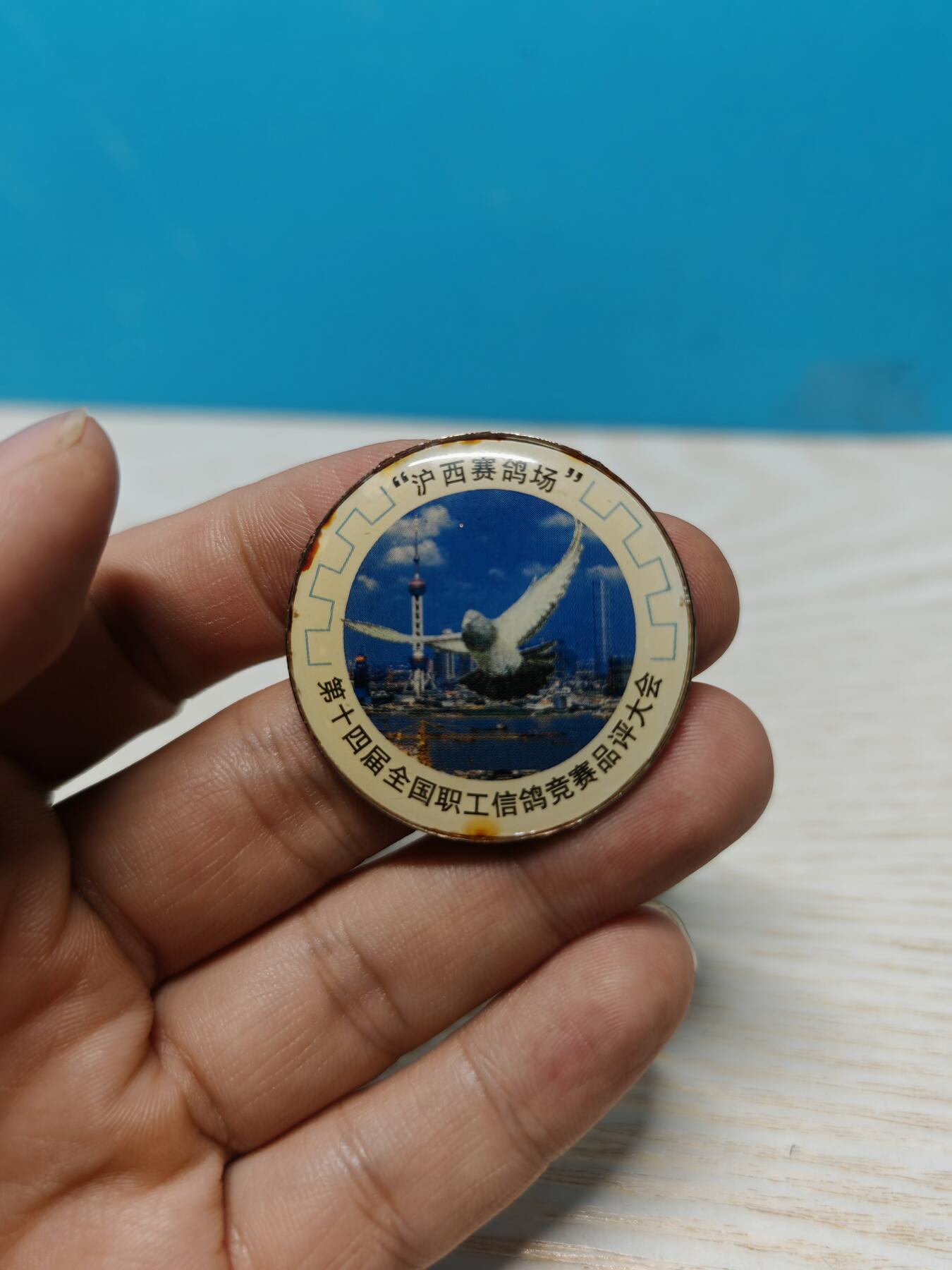 1999年第十四届全国职工信鸽竞赛品评大会纪念章，沪西赛鸽场主题，金属材质，背面1999字样，带别针。品相以图为准，有正常使用痕迹，整体保存不错，适合信鸽、赛事、纪念章收藏。
