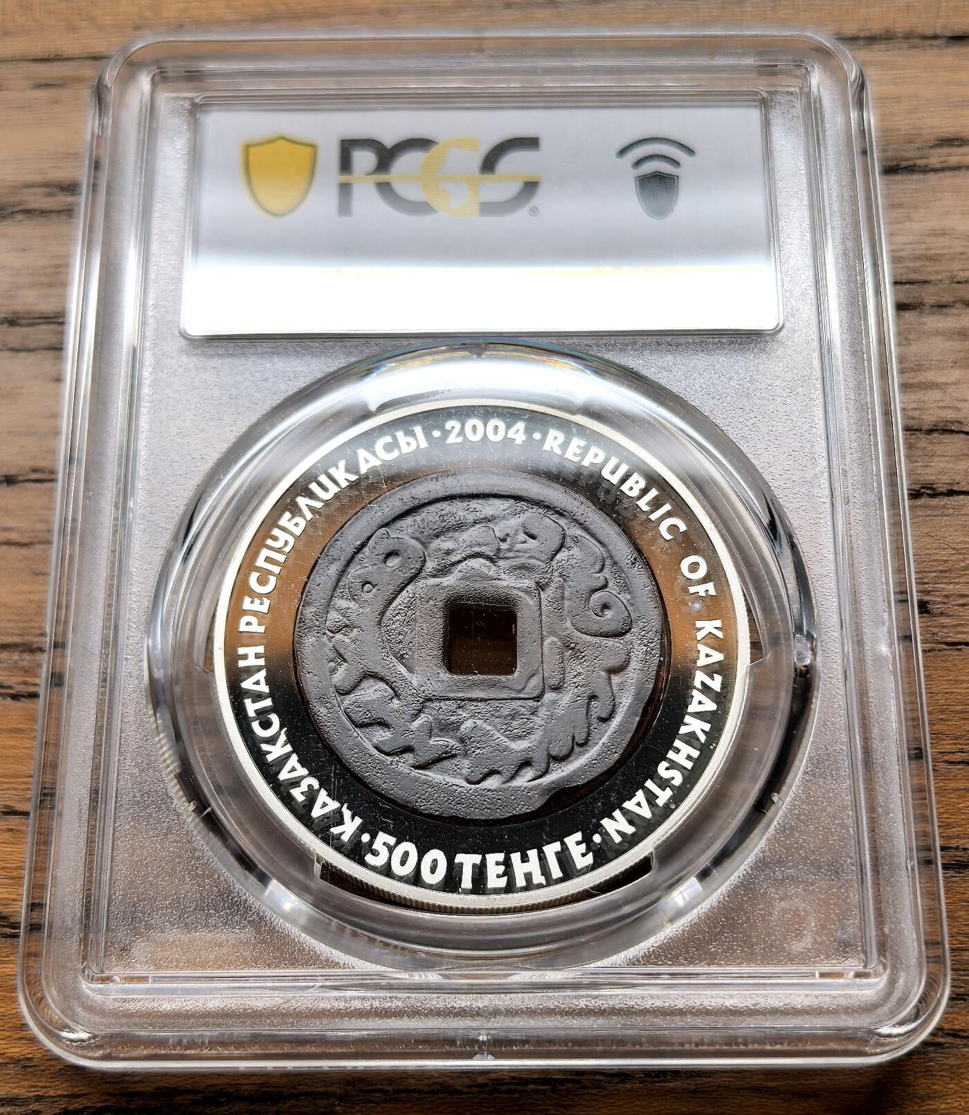 凡希社世界钱币微拍第三百二十二期 2004哈萨克斯坦“Denga”币中币500坚戈大银精铸PCGS-PR69DCAM，Denga是沙俄时期的小额货币单位，价值1/2戈比，最早起源于14世纪的金帐汗国银币仿制币，彼得大帝时期定型为铜质辅币，是俄罗斯“钱（деньги）”一词的词源，该币是哈萨克斯坦“古代钱币系列”首枚，币面中心复刻了古代Denga钱币的纹样，稀缺品种。