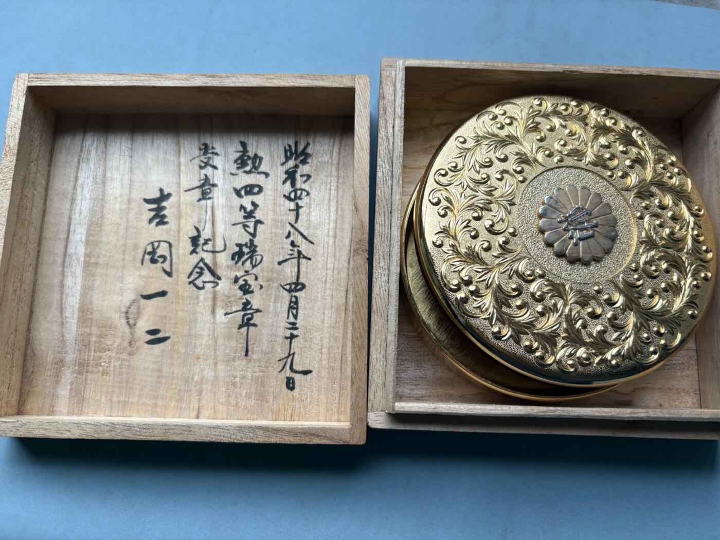 盛世勋华——号角文化勋章邮票专场拍卖第314期 日本昭和48年（1973年）勋四等瑞宝章受章纪念金盒，原桐木盒带受章人吉冈一二手书铭文，满工唐草纹錾刻，中心菊纹嵌银“勋”字，工艺精湛，大尺寸