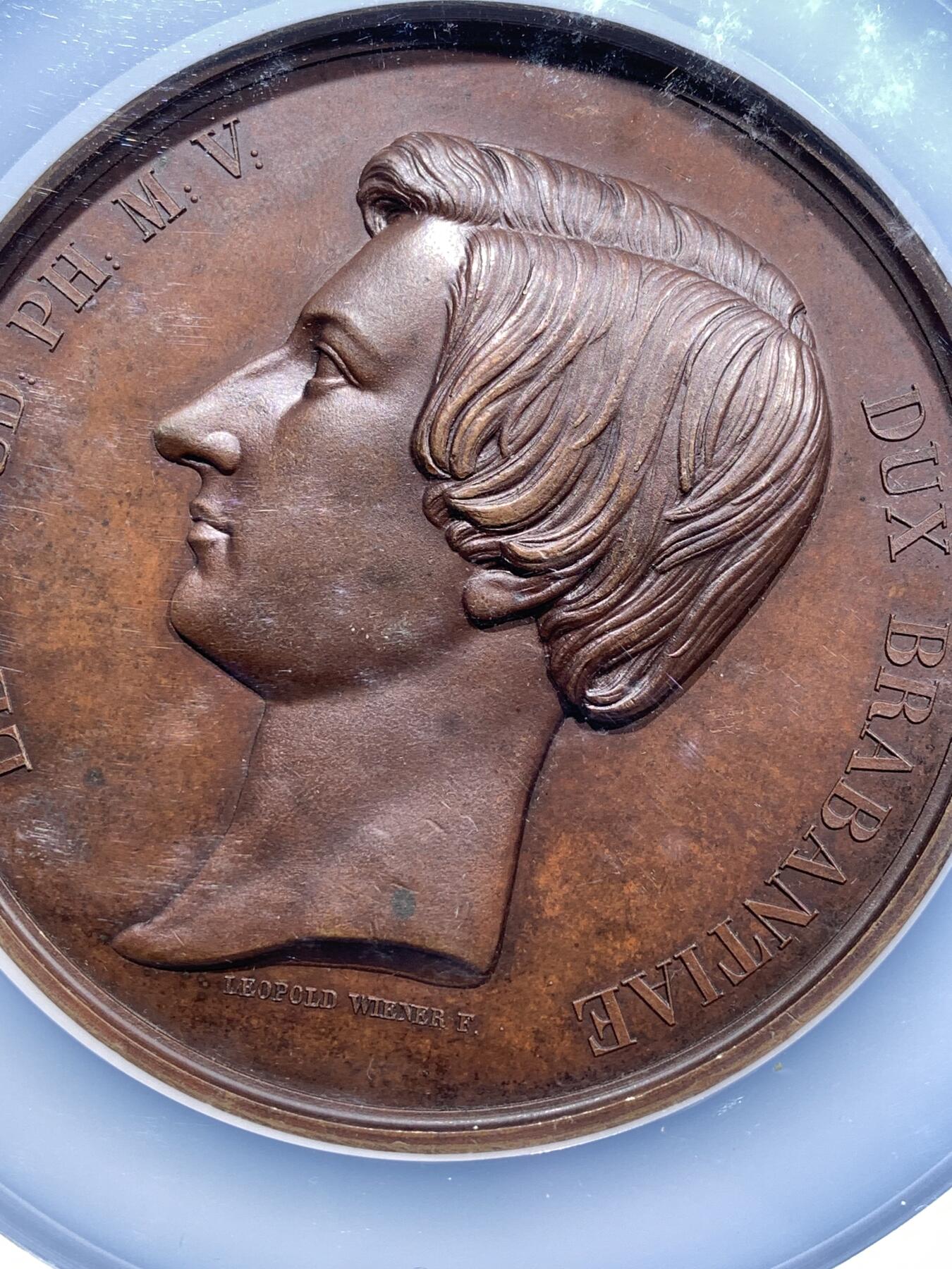 《竞宝斋》第481场 周日，周一 2场连拍 （全场包邮）20级店铺 欢迎送拍 NGC MS64BN 比利时1853年利奥波德二世成年宣誓制造大规格铜章，由著名章牌雕刻师Leopold Wiener设计制作（大名定鼎鼎），该章是王室章牌中的经典藏品。英国皇家收藏、法国国家图书馆、澳大利亚维多利亚馆均有收藏。可见盖该章的历史性和收藏价值。双面高浮雕，巧克力包浆，直径：75mm，重：175g，加大加厚盒装。