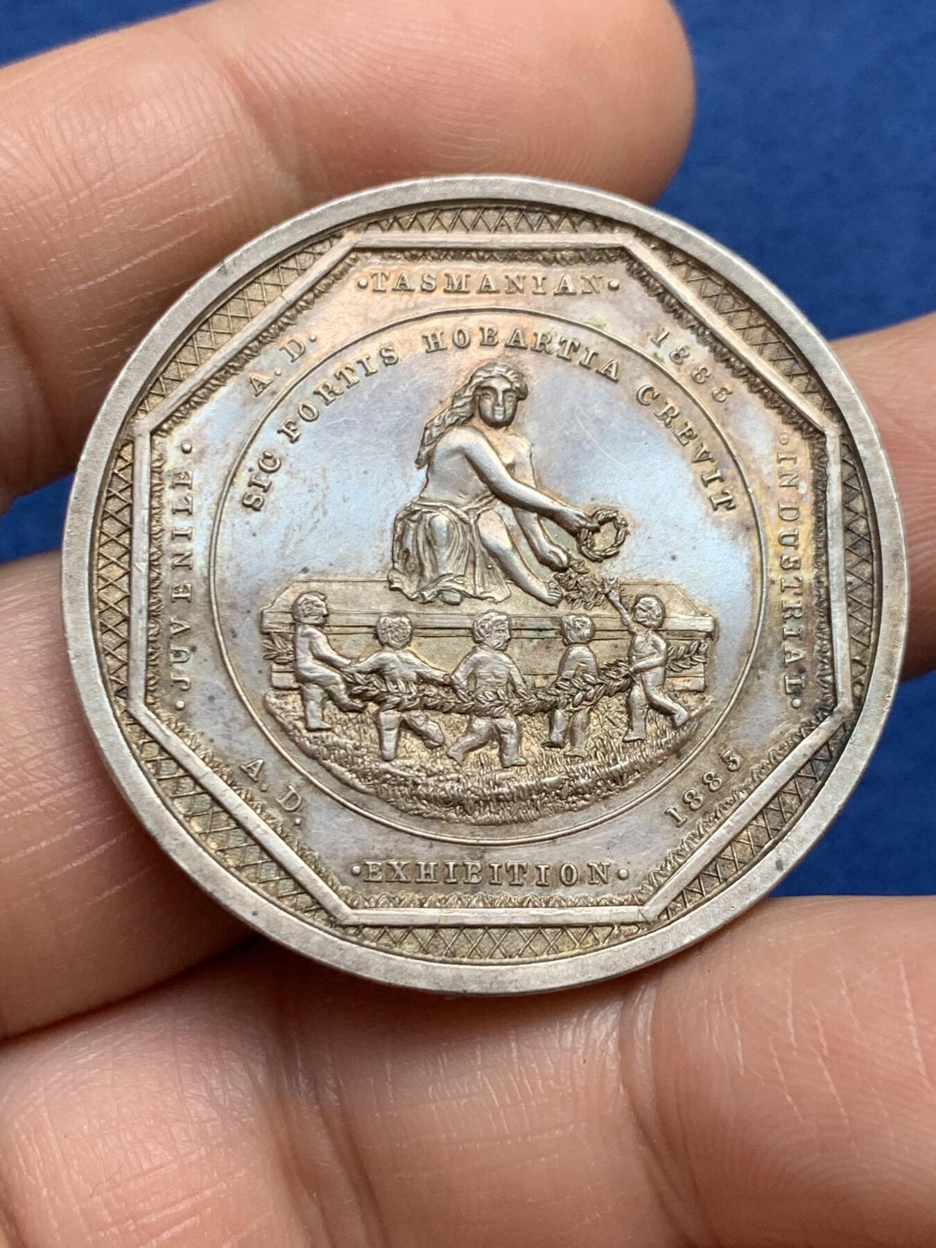《竞宝斋》第482场 周日，周一 2场连拍 （全场包邮）20级店铺 欢迎送拍 澳大利亚塔斯马尼亚霍巴特市工业展览会银质奖章，罕见的外圆内八造型。边有对孔（挂奖牌）。该章是澳大利亚殖民时期极具代表性的收藏品，极少见，历史价值高。由塔斯马尼亚政府及地方议会主办制造。正面图案：描绘了象征霍巴特的拟人化形象坐于祭坛之上，手持花环。铭文译：以此为基，霍巴特日益强盛。背面 拉丁文箴言译为：时代在变，我们亦随之改变；唯有美德（或技艺）是不可或缺的。直径：38.3m，24.6克。