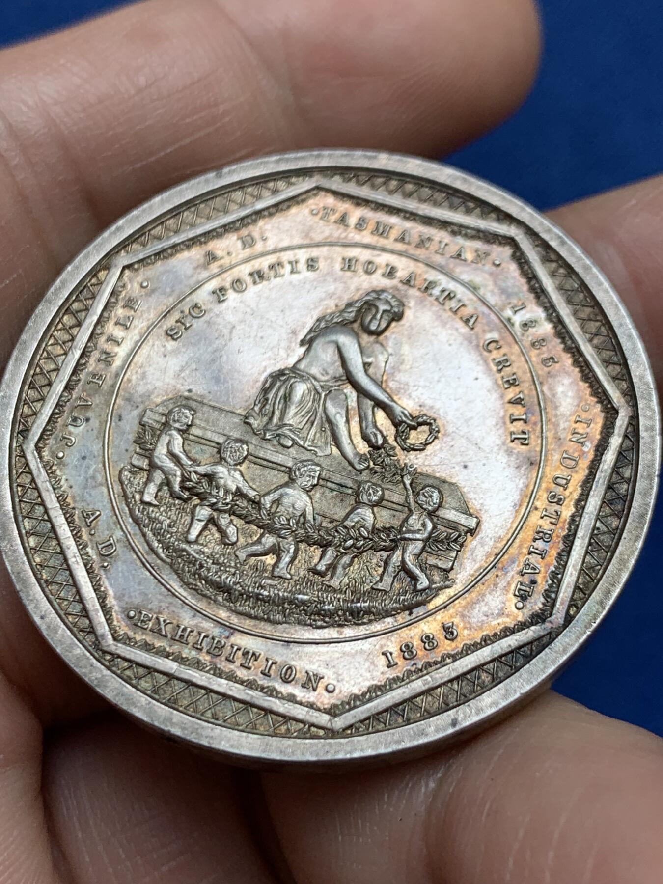 《竞宝斋》第482场 周日，周一 2场连拍 （全场包邮）20级店铺 欢迎送拍 澳大利亚塔斯马尼亚霍巴特市工业展览会银质奖章，罕见的外圆内八造型。边有对孔（挂奖牌）。该章是澳大利亚殖民时期极具代表性的收藏品，极少见，历史价值高。由塔斯马尼亚政府及地方议会主办制造。正面图案：描绘了象征霍巴特的拟人化形象坐于祭坛之上，手持花环。铭文译：以此为基，霍巴特日益强盛。背面 拉丁文箴言译为：时代在变，我们亦随之改变；唯有美德（或技艺）是不可或缺的。直径：38.3m，24.6克。
