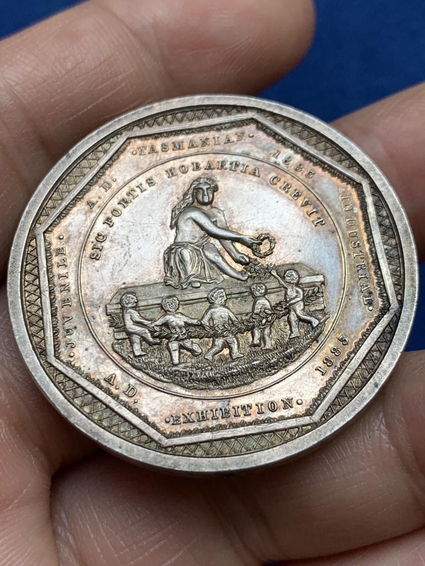 《竞宝斋》第482场 周日，周一 2场连拍 （全场包邮）20级店铺 欢迎送拍 澳大利亚塔斯马尼亚霍巴特市工业展览会银质奖章，罕见的外圆内八造型。边有对孔（挂奖牌）。该章是澳大利亚殖民时期极具代表性的收藏品，极少见，历史价值高。由塔斯马尼亚政府及地方议会主办制造。正面图案：描绘了象征霍巴特的拟人化形象坐于祭坛之上，手持花环。铭文译：以此为基，霍巴特日益强盛。背面 拉丁文箴言译为：时代在变，我们亦随之改变；唯有美德（或技艺）是不可或缺的。直径：38.3m，24.6克。