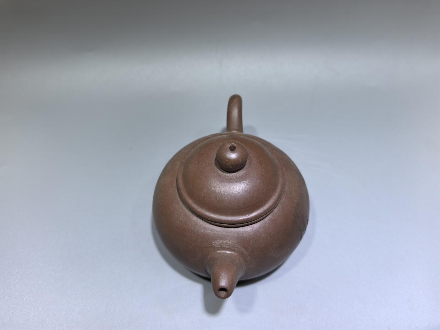 旧藏紫砂老壶，取原矿紫泥为料，泥色温润沉穆，包浆由岁月与茶汤浸润而成，光气内敛，尽显旧物之美。壶型饱满敦实，盖钮圆润如珠，壶流短直流畅，壶把圈握趁手，整体线条简练流畅，颇具传统工夫茶器的朴雅气质。高约6.0cm长约10.5cm