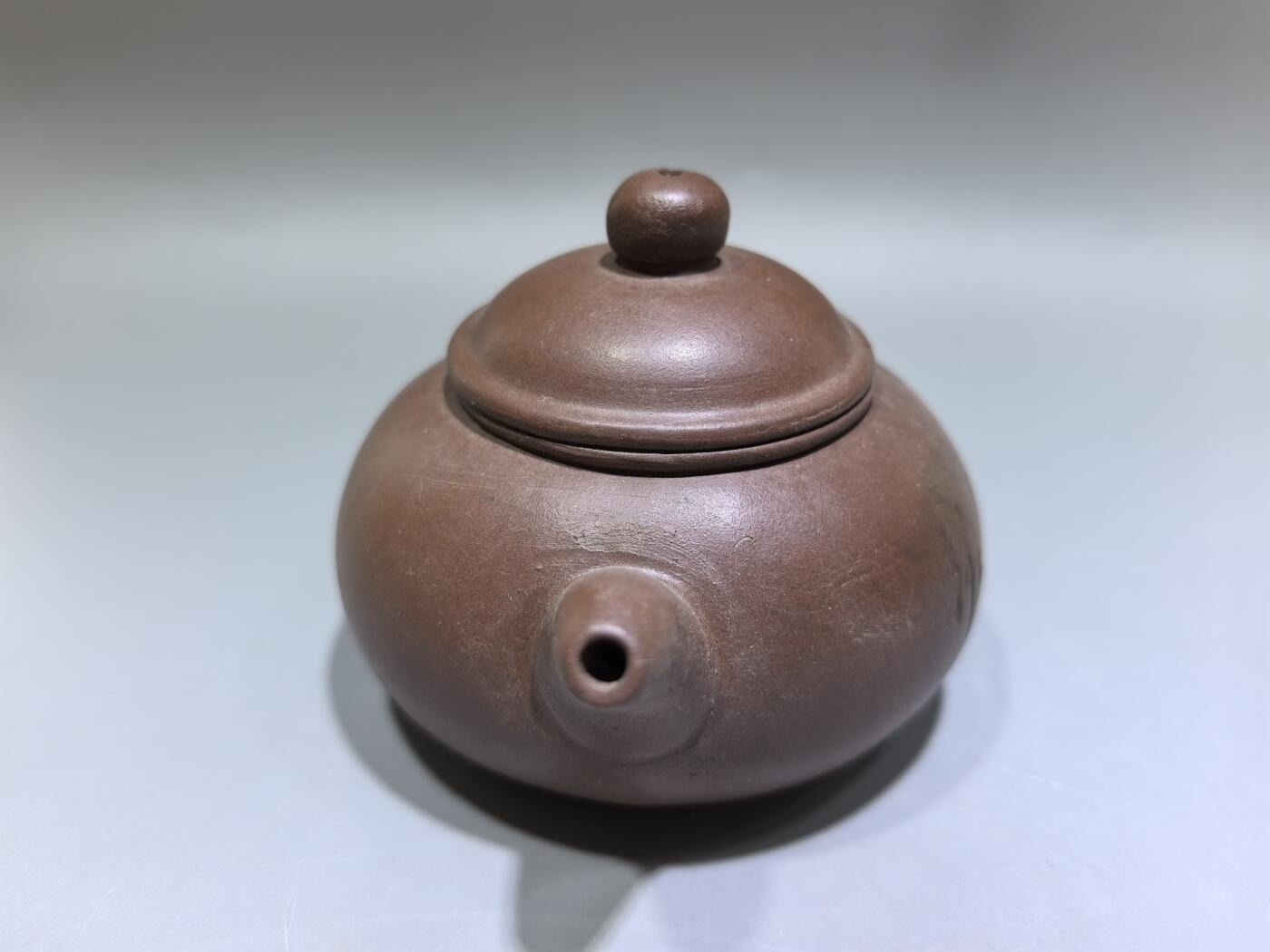 旧藏紫砂老壶，取原矿紫泥为料，泥色温润沉穆，包浆由岁月与茶汤浸润而成，光气内敛，尽显旧物之美。壶型饱满敦实，盖钮圆润如珠，壶流短直流畅，壶把圈握趁手，整体线条简练流畅，颇具传统工夫茶器的朴雅气质。高约6.0cm长约10.5cm