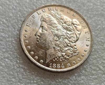 瓶子🏺第257期拍卖会 -  1884‑O 摩根银元（Morgan Silver Dollar）   O标记：新奥尔良造币厂，含银90%，银重24.06g，直径38.1mm ​ - 正面自由女神头像，背面展翅鹰徽 ​ 发行量3,915,000枚，属于比较常见的摩根年份